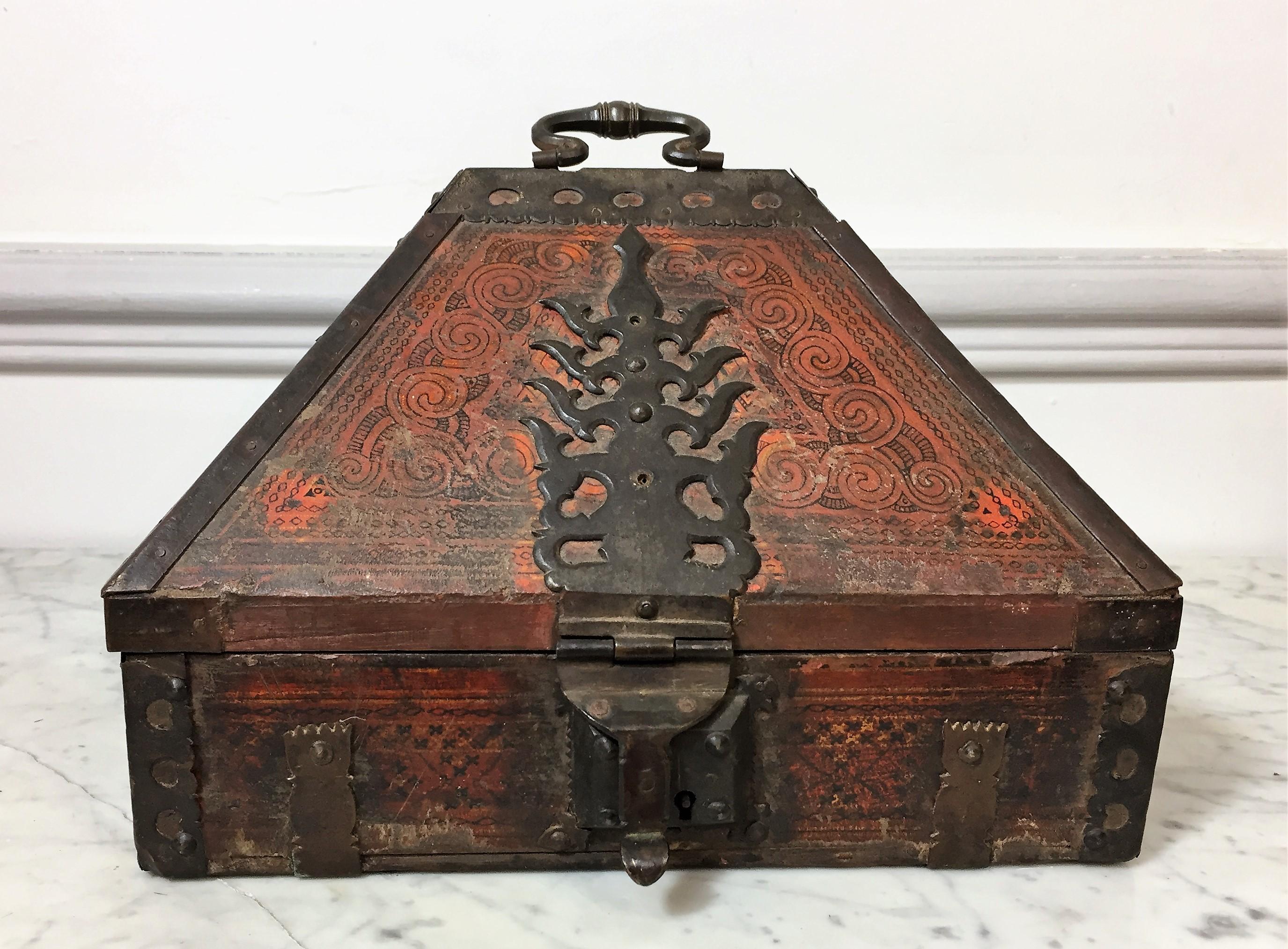 This beautiful travel chest is Indo-Portuguese from the 19th century. The lid is pyramid shaped and the bronze hardware on top is in the form of a stylized flame. The wood is painted with arabesque and geometric patterns. Inside the chest is a