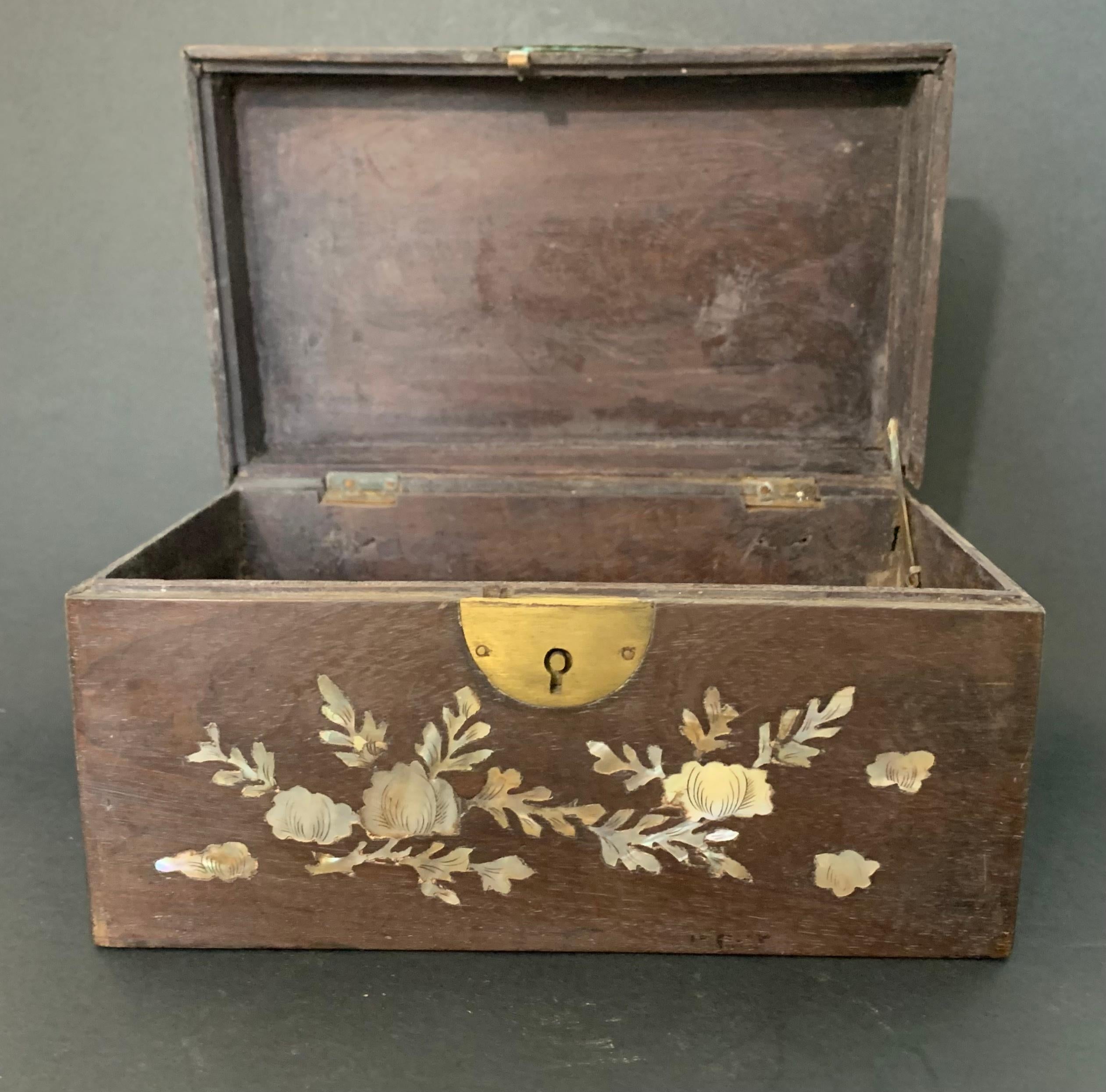 Nice wooden and mother-of-pearl box from the 1900s. The mother-of-pearl inlays form plant motifs (flowers and foliage), incised to give volume to the different parts. It closes with a round lock in the front, made of gilded metal. The wood is a