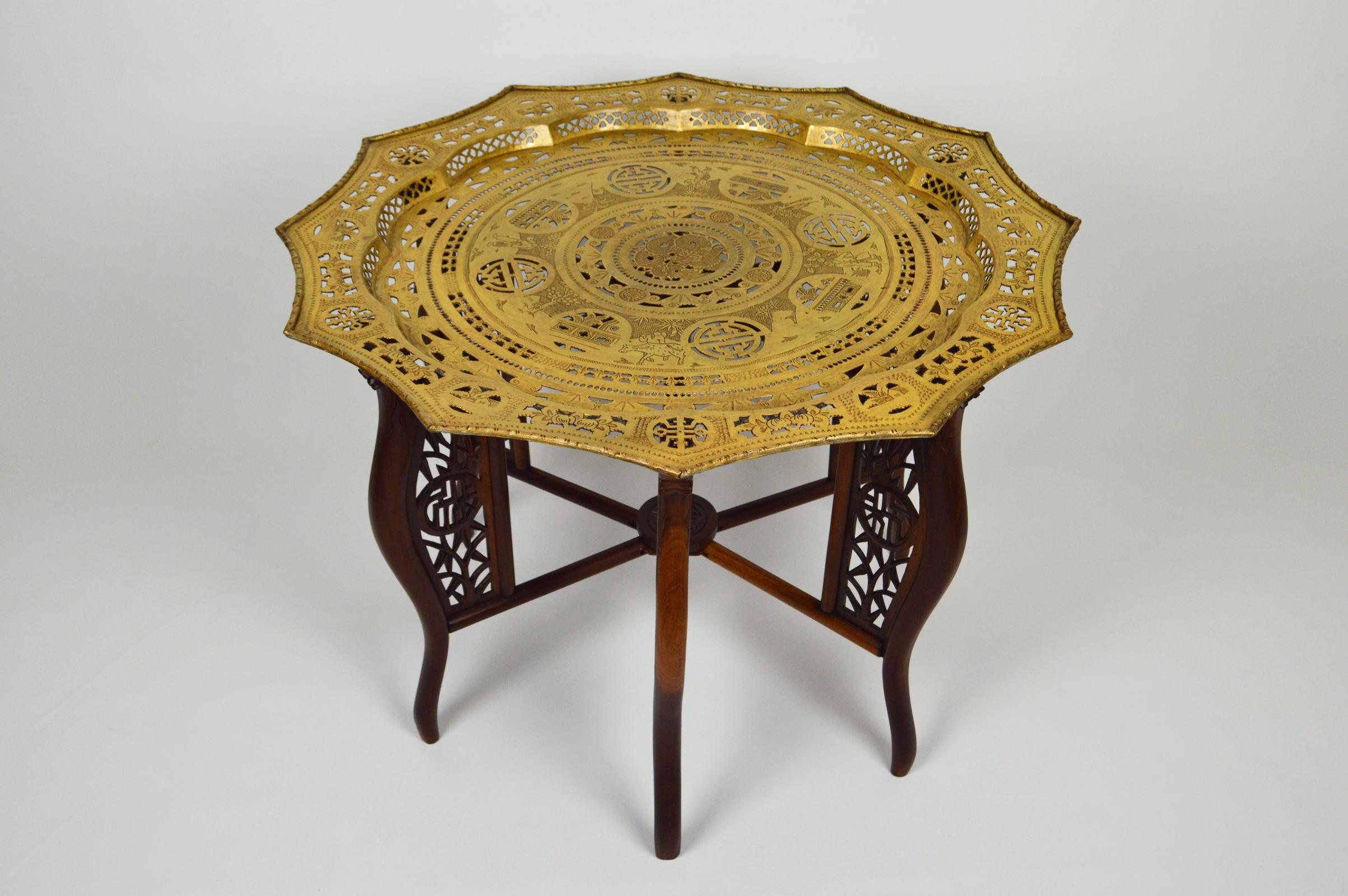 Wonderful tray table/tea or coffee table.

Folding base in carved solid wood, with dragons, bamboos and medallions/symbols.

Brass tray, with bronze patina. Richly decorated, with scenes of a Indochinese village life, a fisherman, two farmers,