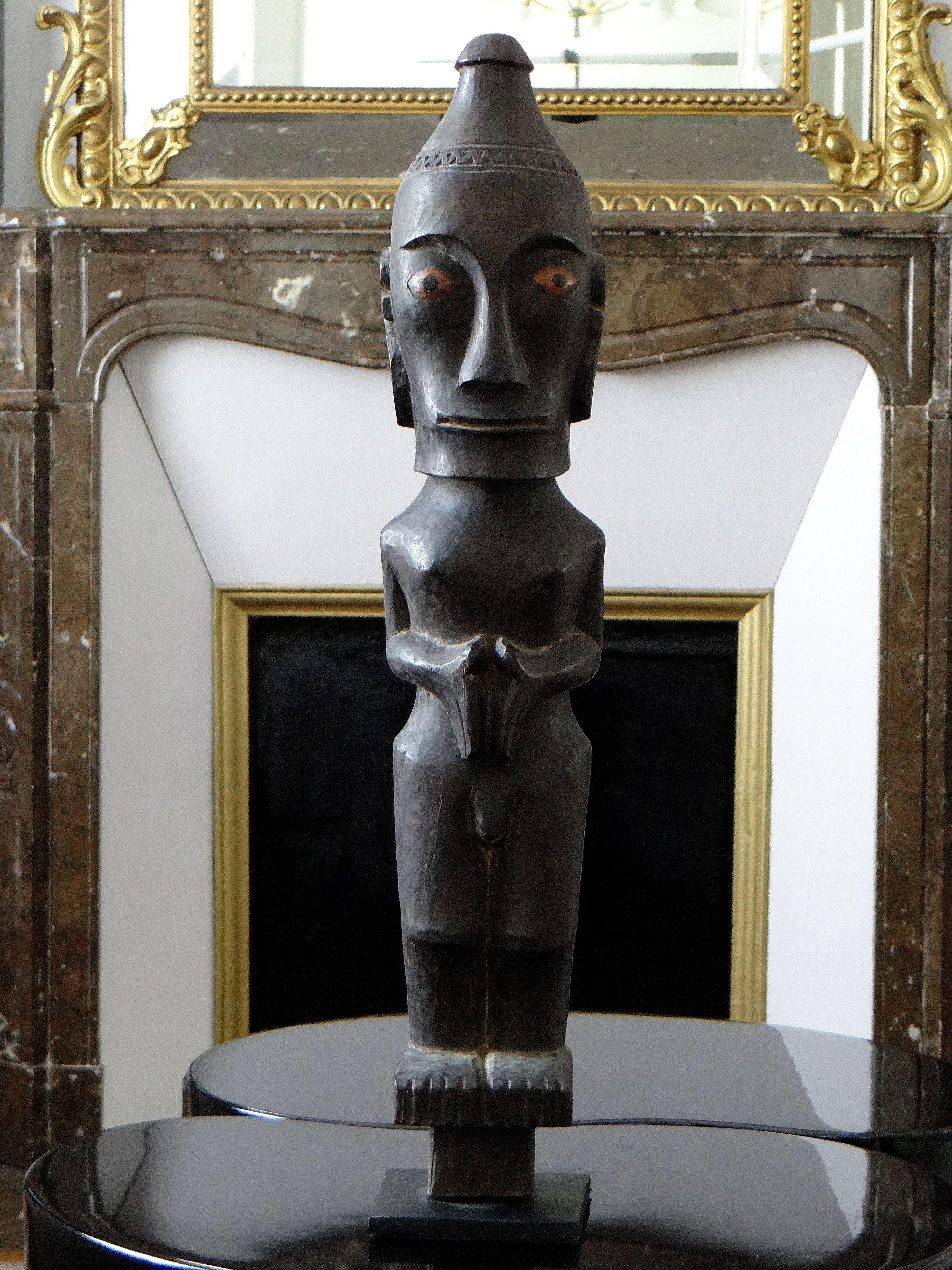 Beautiful Indonesian statue of the Batak Toba people, Sumatra island, carved patinated wood from the 1960s showing a character but joined and slightly bent legs whose gaze fixed a distant point. Very good quality of the sculpture and beautiful