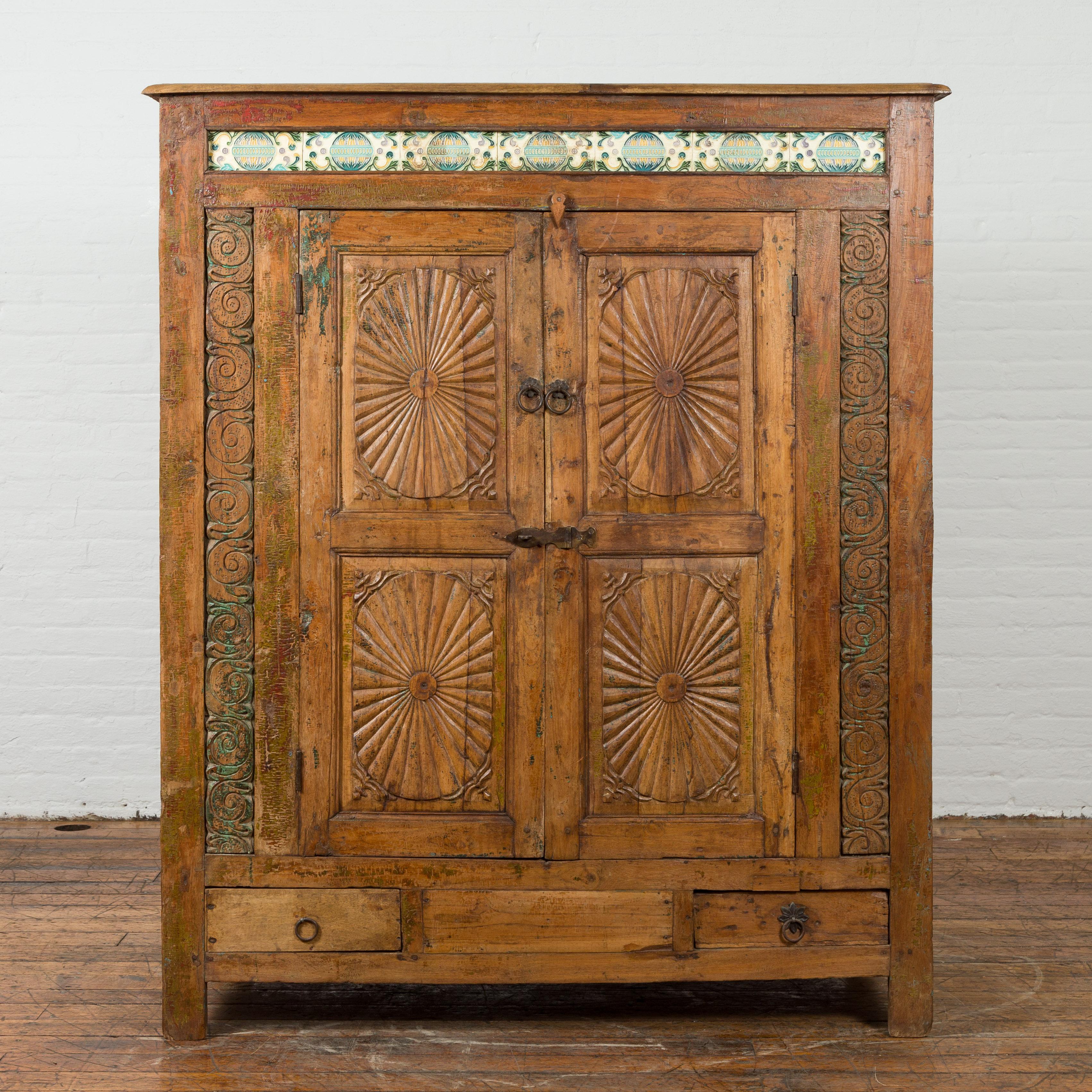 Our beautiful Indonesian large antique cabinet from the 19th century is a stunning addition to our extensive vintage and antique cabinets collection. This tall wooden antique cabinet features eye-catching blue and yellow enameled tiles at the top