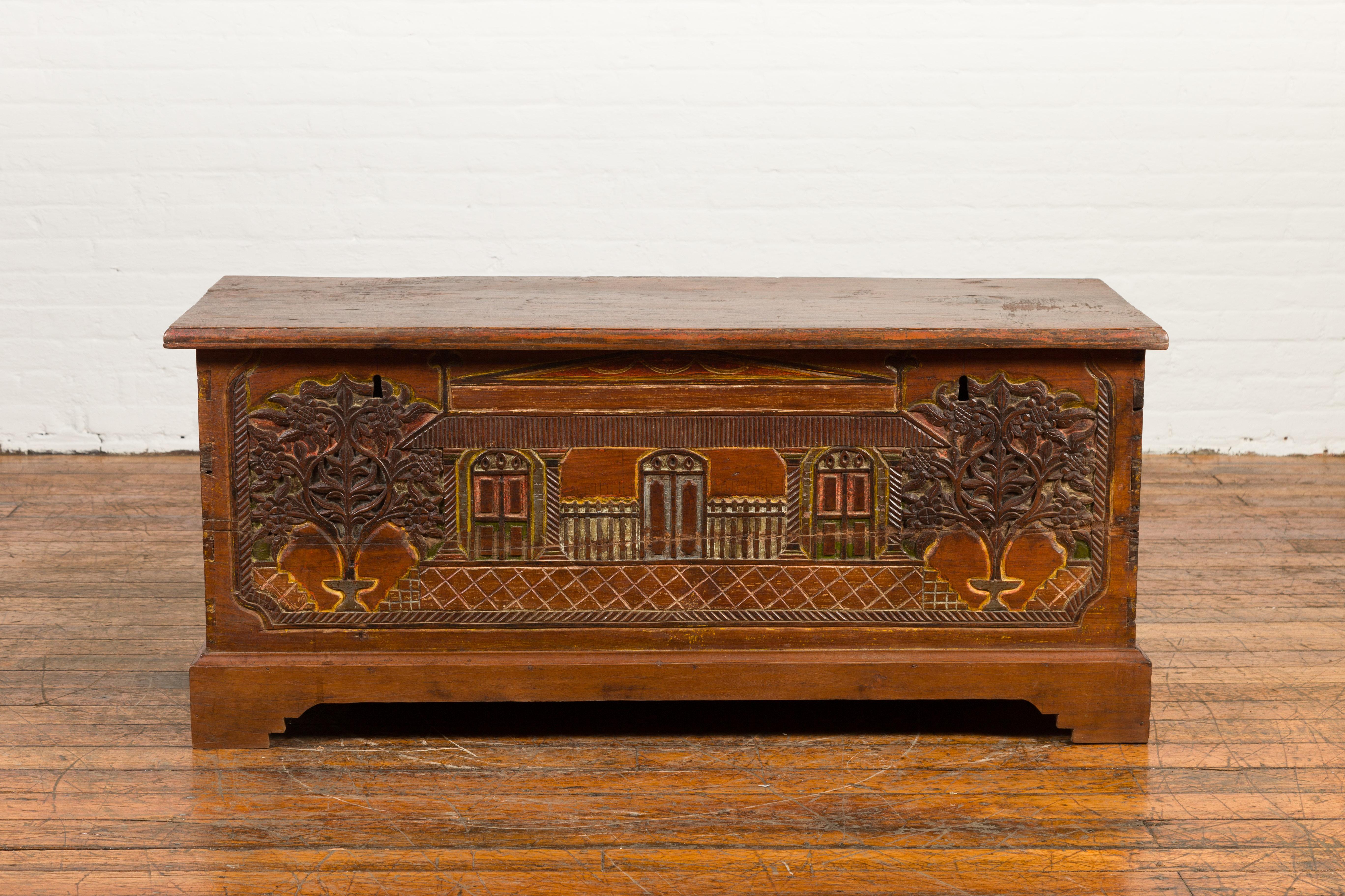 An Indonesian carved and painted trunk from the 19th century, with architecture and foliage. Created in Indonesia during the 19th century, this trunk, ideal to be used as a blanket chest, features a rectangular lid that opens up to reveal a