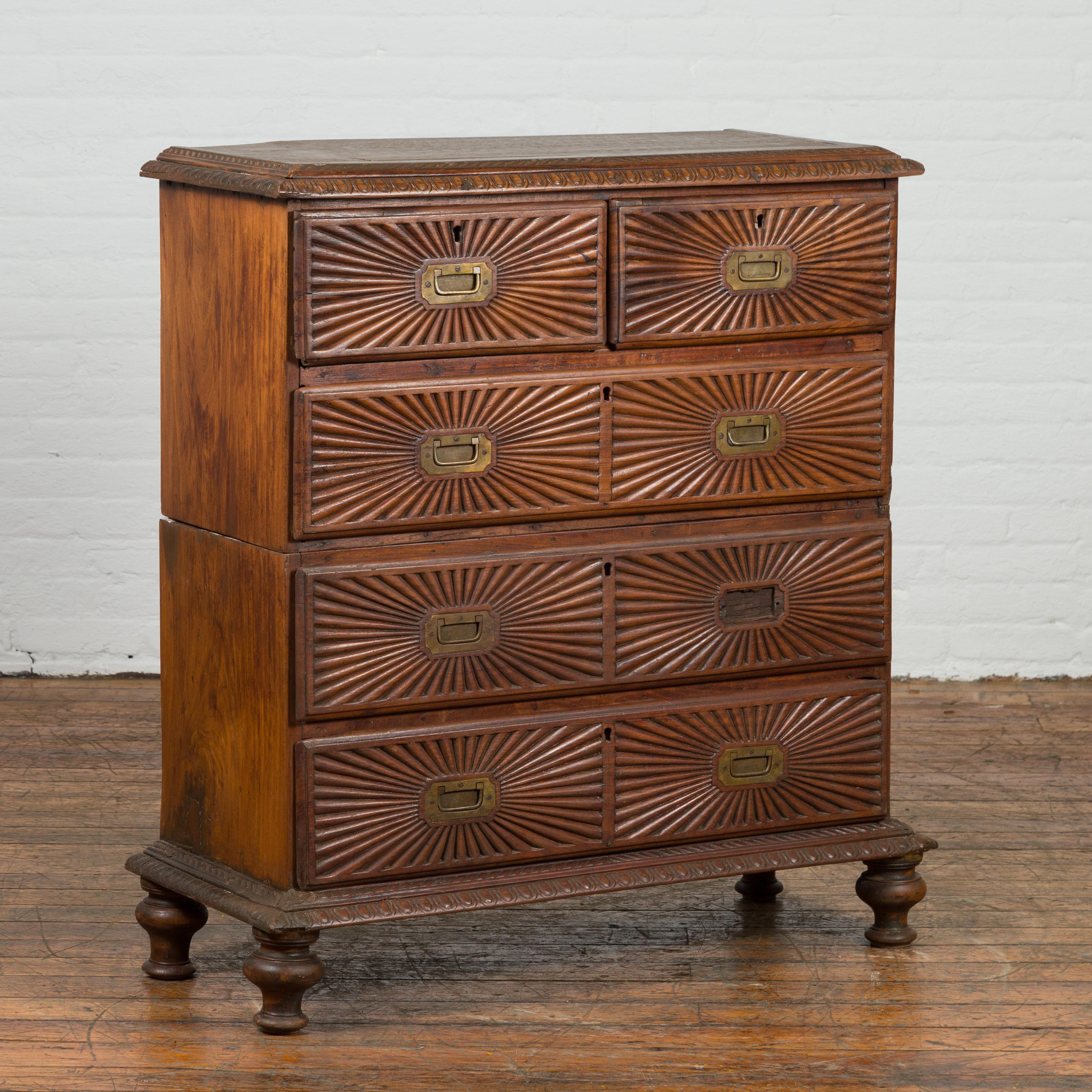 An Indonesian five-drawer chest from the 19th century, with carved sunburst and ovoid motifs. Created in Indonesia during the 19th century, this tall chest features a rectangular top with beveled edges surrounded by a carved ovoid frieze. The façade