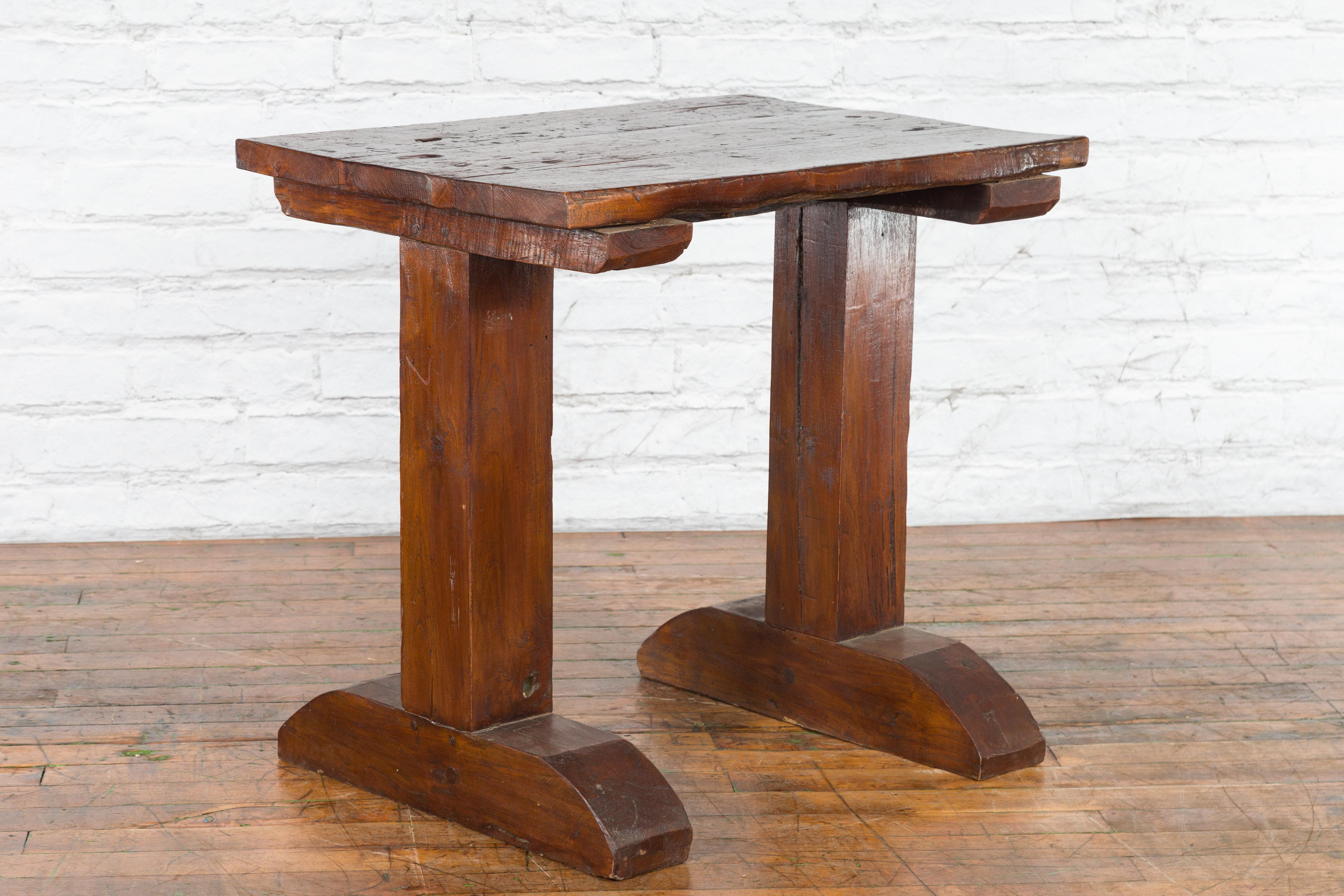 An antique Indonesian wooden wine tasting table from the 19th century, with rustic appearance. Created in Indonesia during the 19th century, this wine tasting table features a rectangular planked top with nicely worn patina, sitting above a trestle