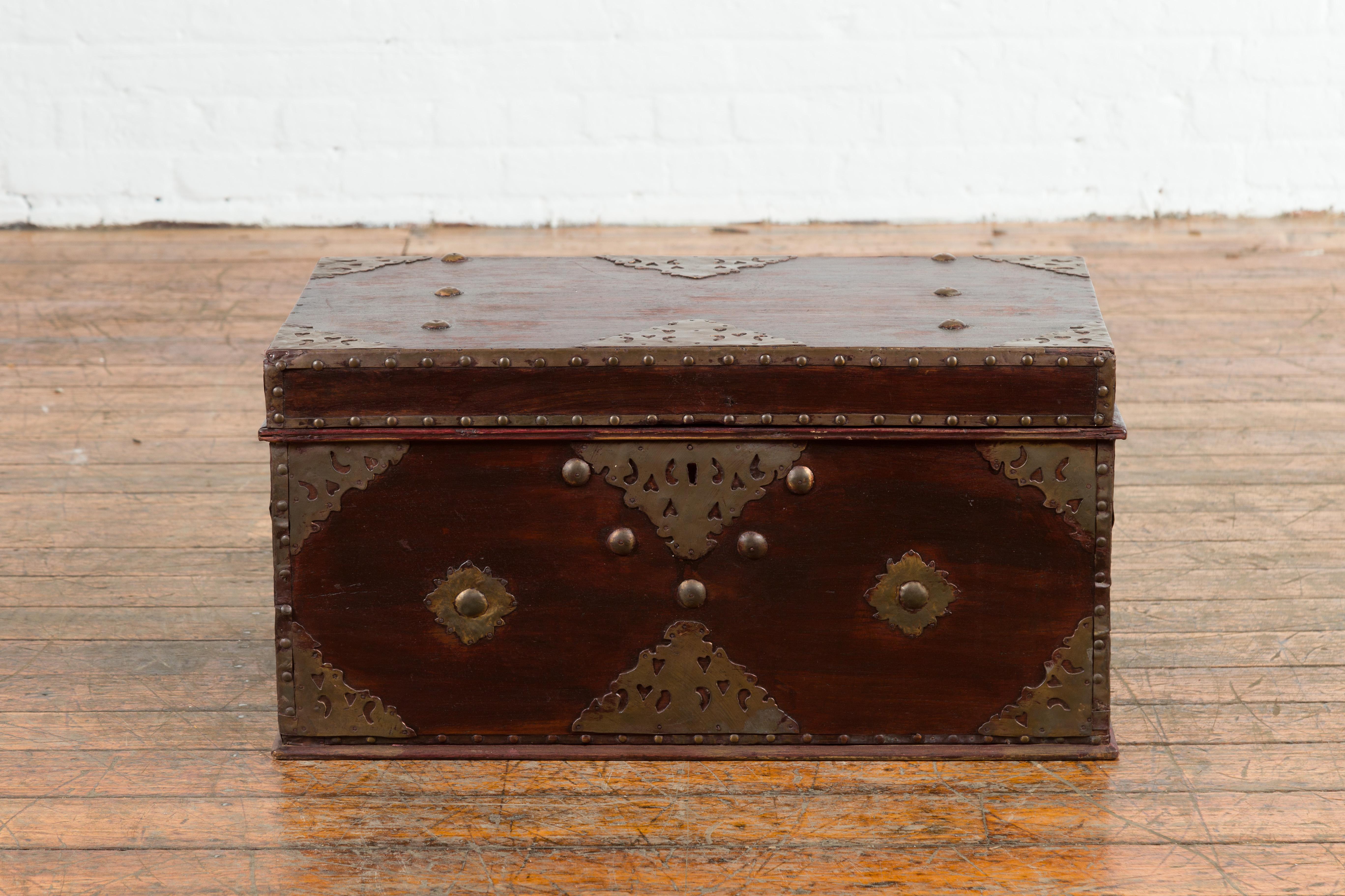 An Indonesia antique wooden blanket chest from the 19th century, with detailed brass hardware. Created in Indonesia during the 19th century, this unusual blanket chest features a wooden body adorned with ornate cut-out brass hardware and studs. The