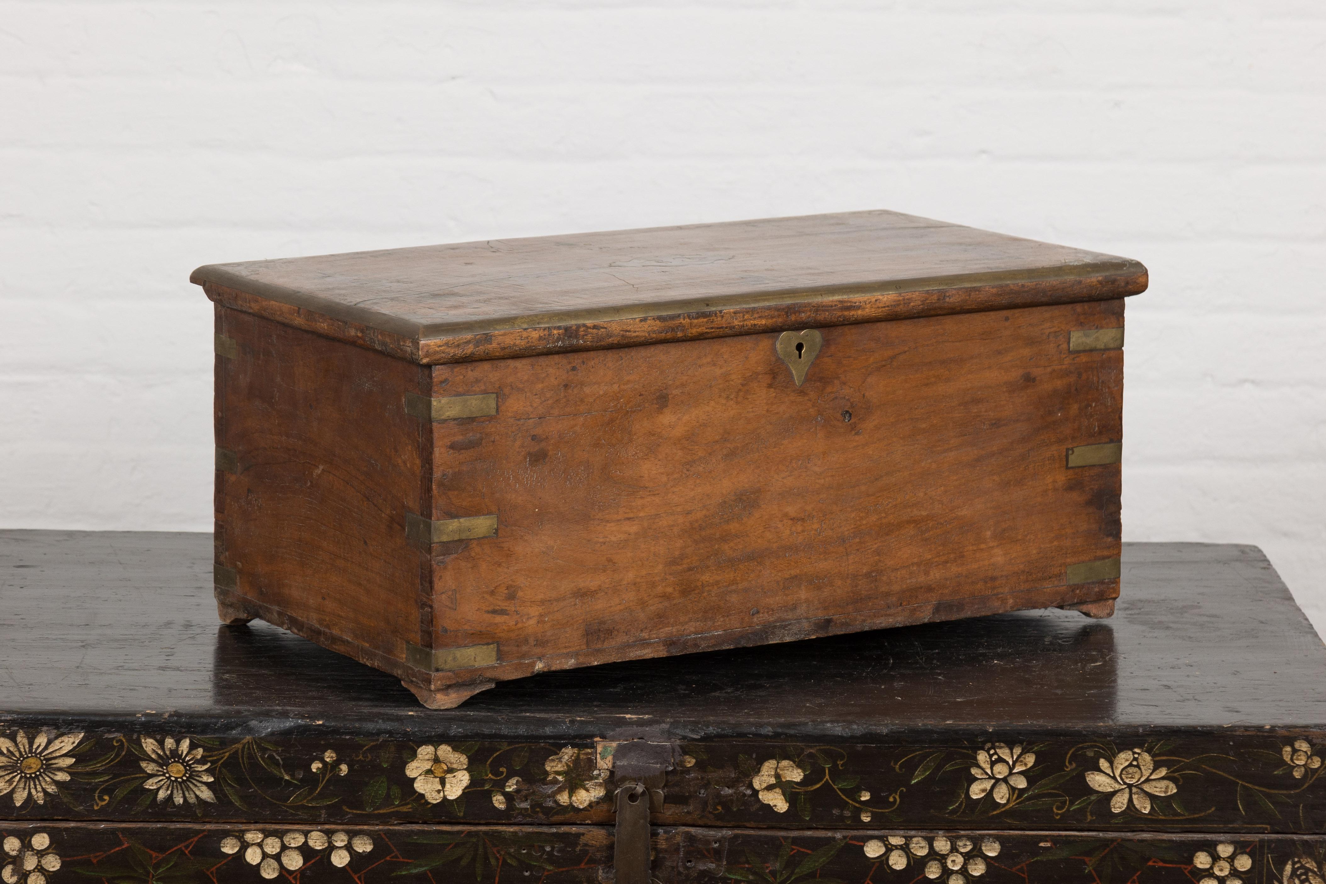 An old Indonesian wooden box from the 19th century with inlaid brass details, partitioned interior and rustic character. Caressing the annals of time with rustic elegance, this old Indonesian wooden box from the 19th century weaves tales of ancient