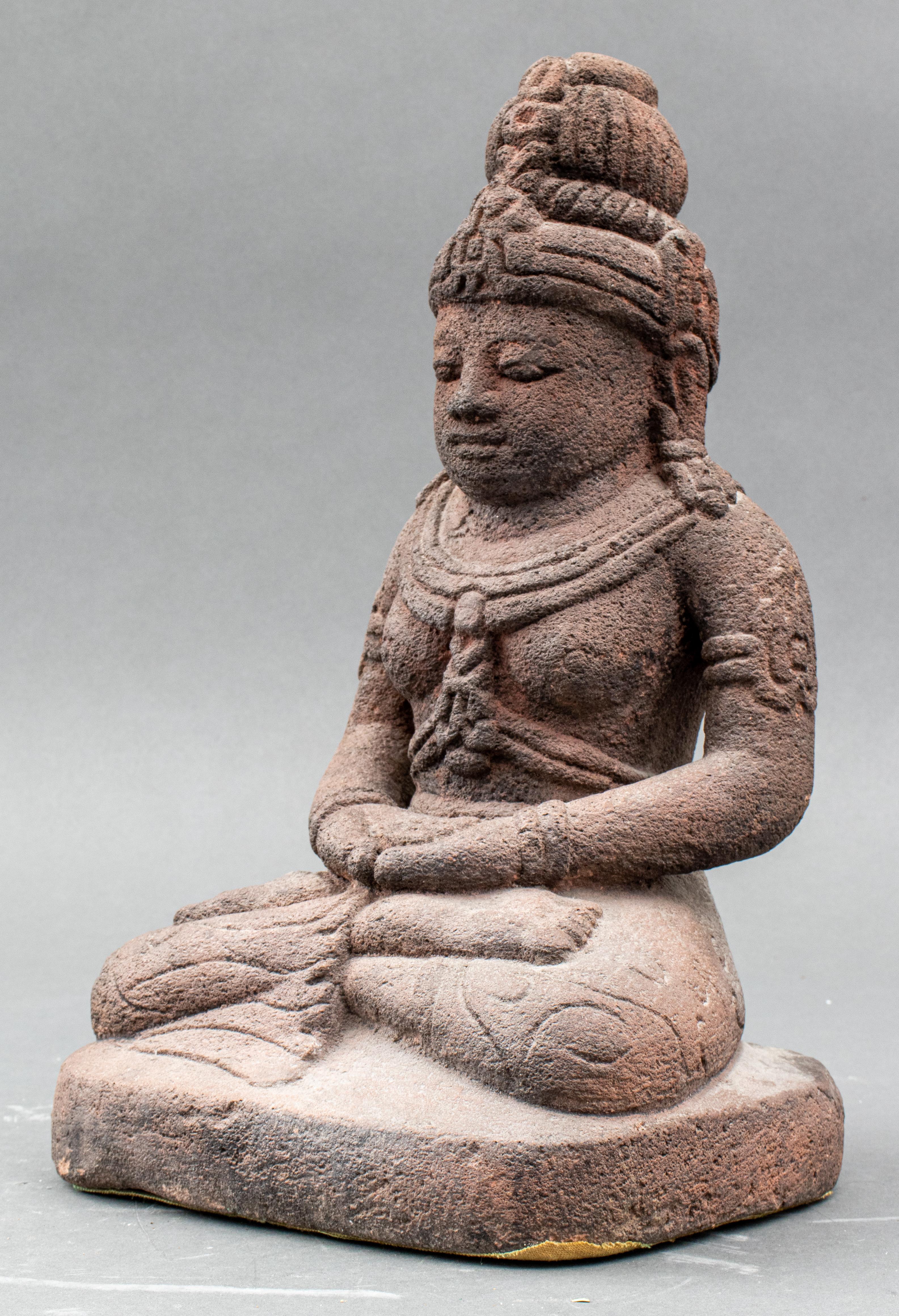 Indonesian andesite figure depicting a seated bodhisattva in lotus position / padmasana wearing armbands, earrings, bracelets, necklaces, pants with carved scrolling design, and a headdress, Java, 16th century or later. 
Measures: 15.5