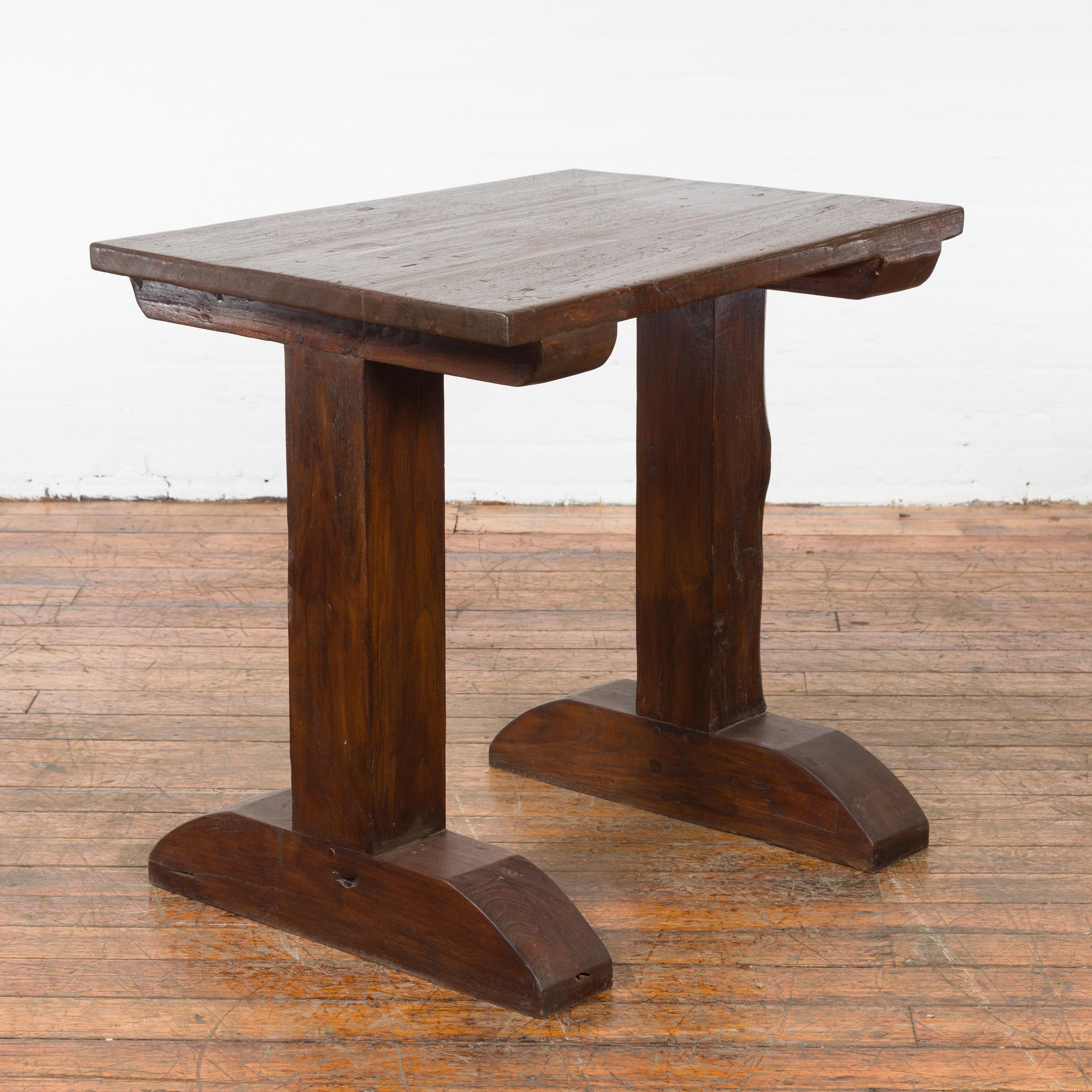 An Indonesian antique wine tasting table from the 19th century with trestle base. Created in Indonesia during the 19th century, this wine tasting table features a rectangular top sitting above a trestle base (sans stretcher). Boasting a nicely