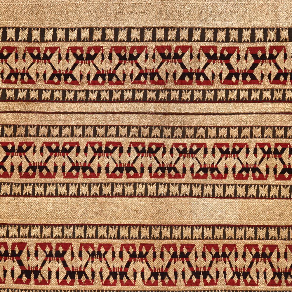 Indonesian ceremonial skirt (Tapis) from the Abung people of Lampung, Sumatra with dense linear abstract design of gold-wrapped thread couched down to the multi-coloured linear cotton red and blue striped background.
Condition: Skirt seam opened and