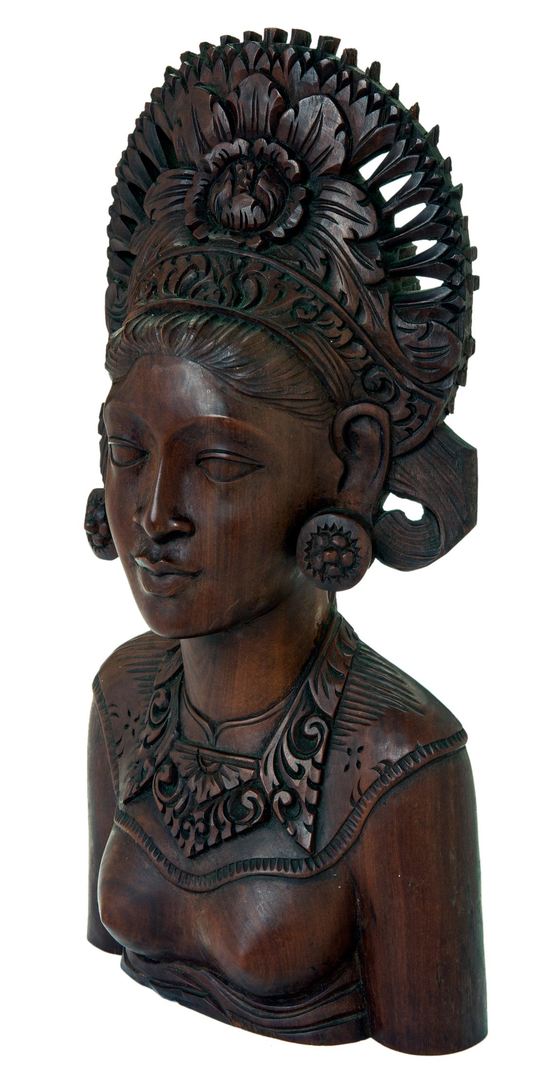 Goddess of rice and fertility, still widely worshiped in some areas of the world. Her giant reticulated crown features a large carved flower medallion and swirling floral neck breastplate. She wears round earrings decorate with a concentric flower