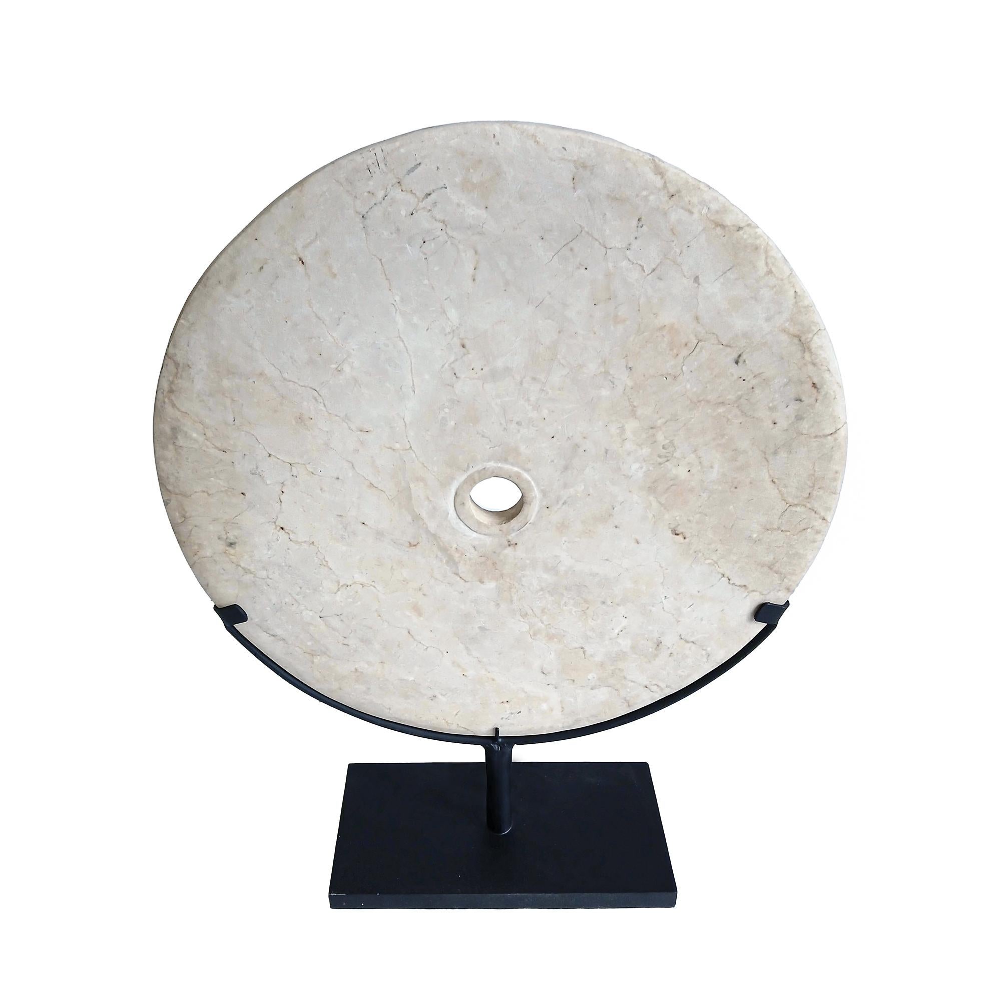 A cream-colored marble disk, hand-carved in Indonesia, contemporary. 

Reminiscent of the traditional 