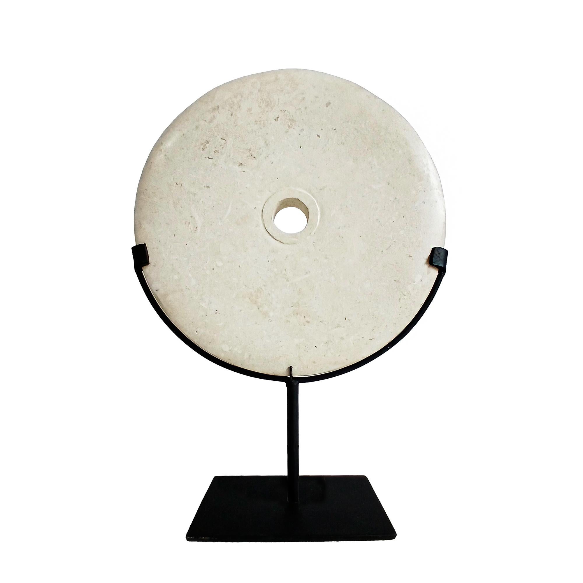 A cream-colored marble disk, hand-carved in Indonesia, contemporary. 

Reminiscent of the traditional 