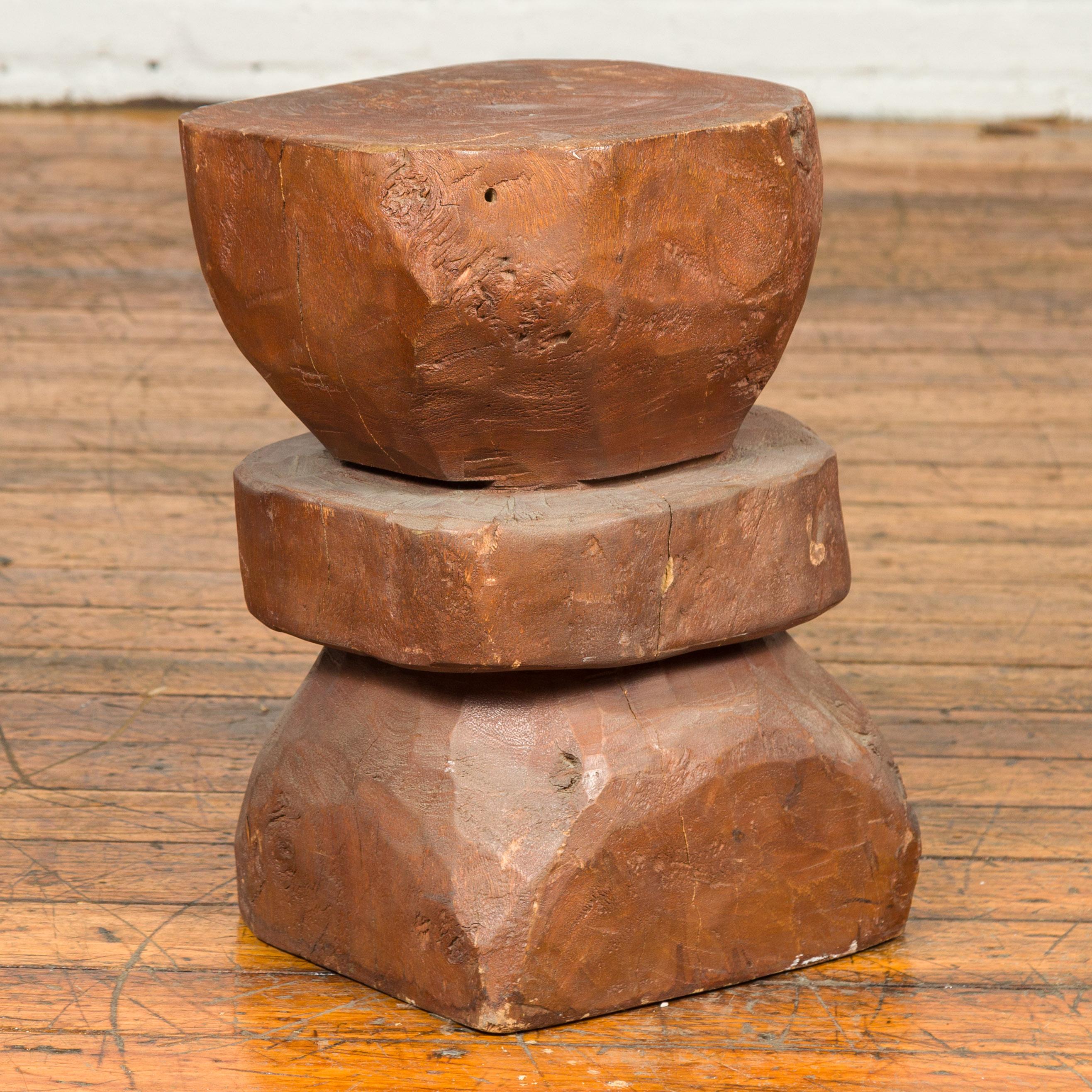 A Indonesian rustic tree stump pedestal from the late 20th century, with hourglass shape. Crafted in Indonesia, this pedestal will charm you with its rustic appeal and interesting shape. Made of a tree stump roughly carved into geometrical shapes,