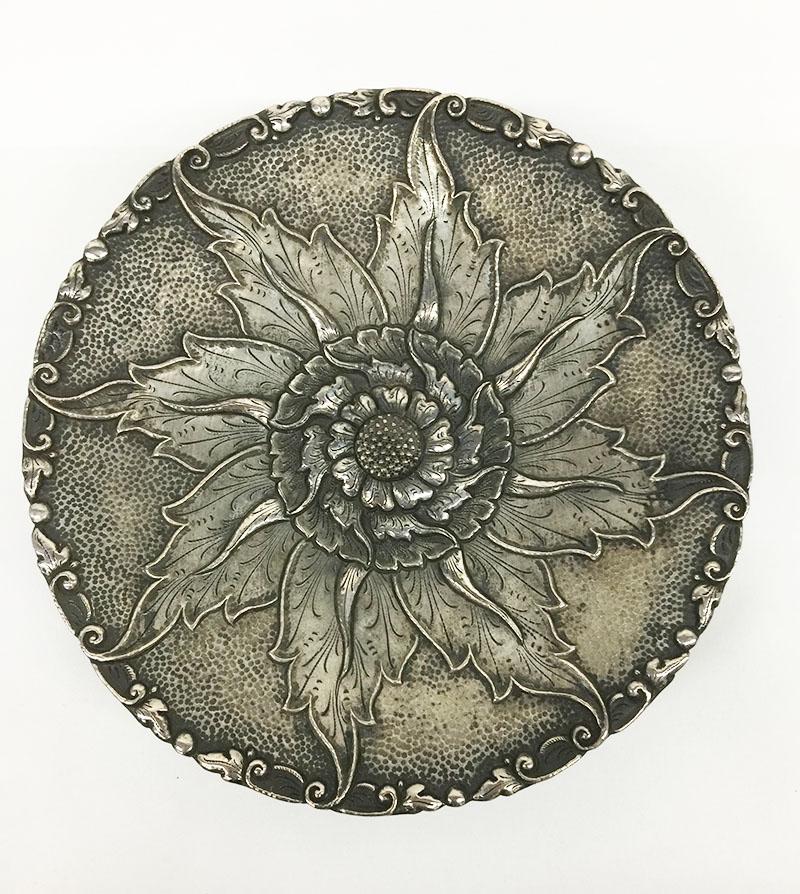 Plat à trois pieds en argent indonésien Yogya avec motif floral

Marqué avec S800 
Sur le bord, une petite scène de feuilles et, au centre, une fleur en relief.
en partie martelée, surélevée sur 3 pieds lisses sous la base 
On sait que l'argent
