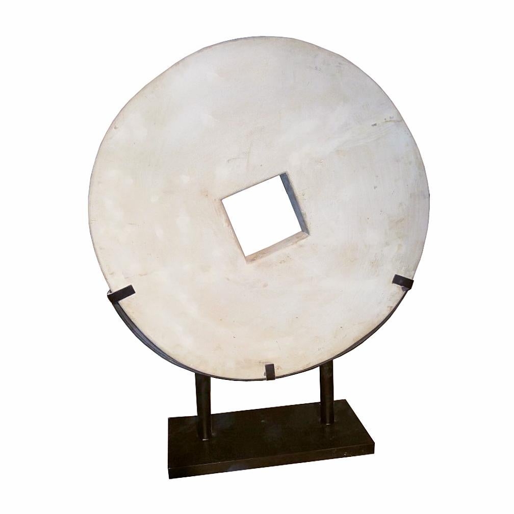 A large hand-carved stone coin from Indonesia, square-shaped center. Rustic finishing, natural off-white color. Mounted on a 18