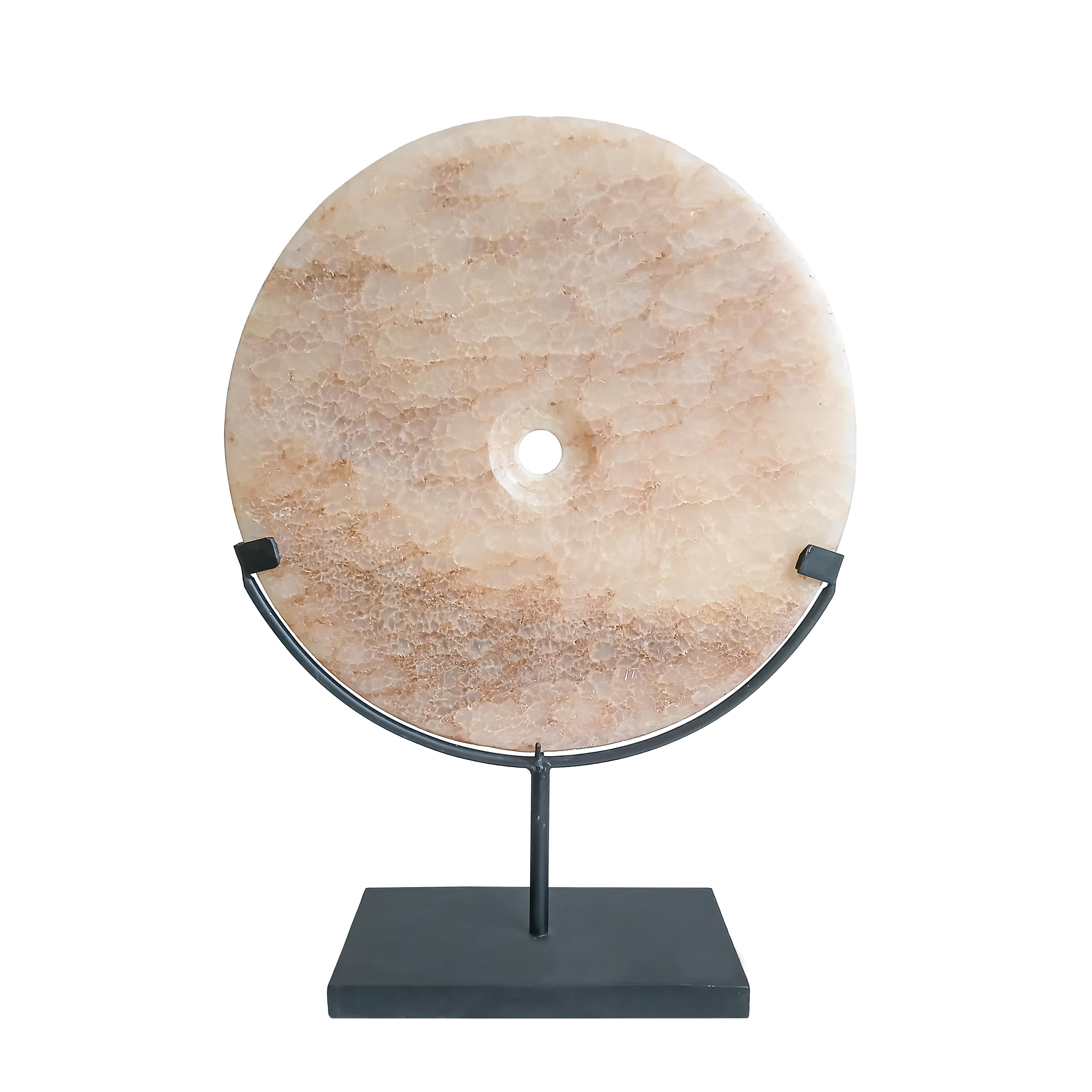 A pink stone disk, hand-carved in Indonesia, contemporary. 

Reminiscent of the traditional 