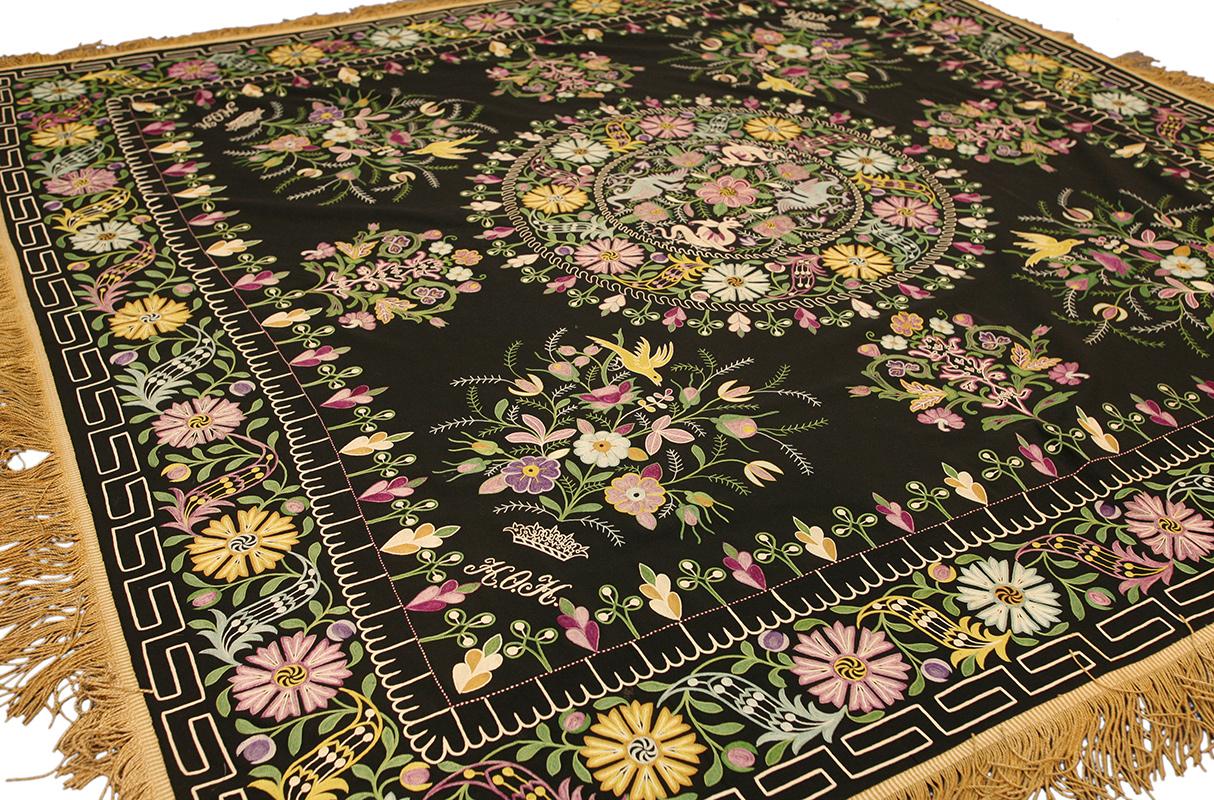 Ce magnifique textile indonésien, mesurant 172 × 172 cm, est une étoffe de cérémonie brodée à la main de format carré, probablement destinée à un mariage ou à une dot. Sur un riche fond noir, la composition présente un étonnant médaillon central