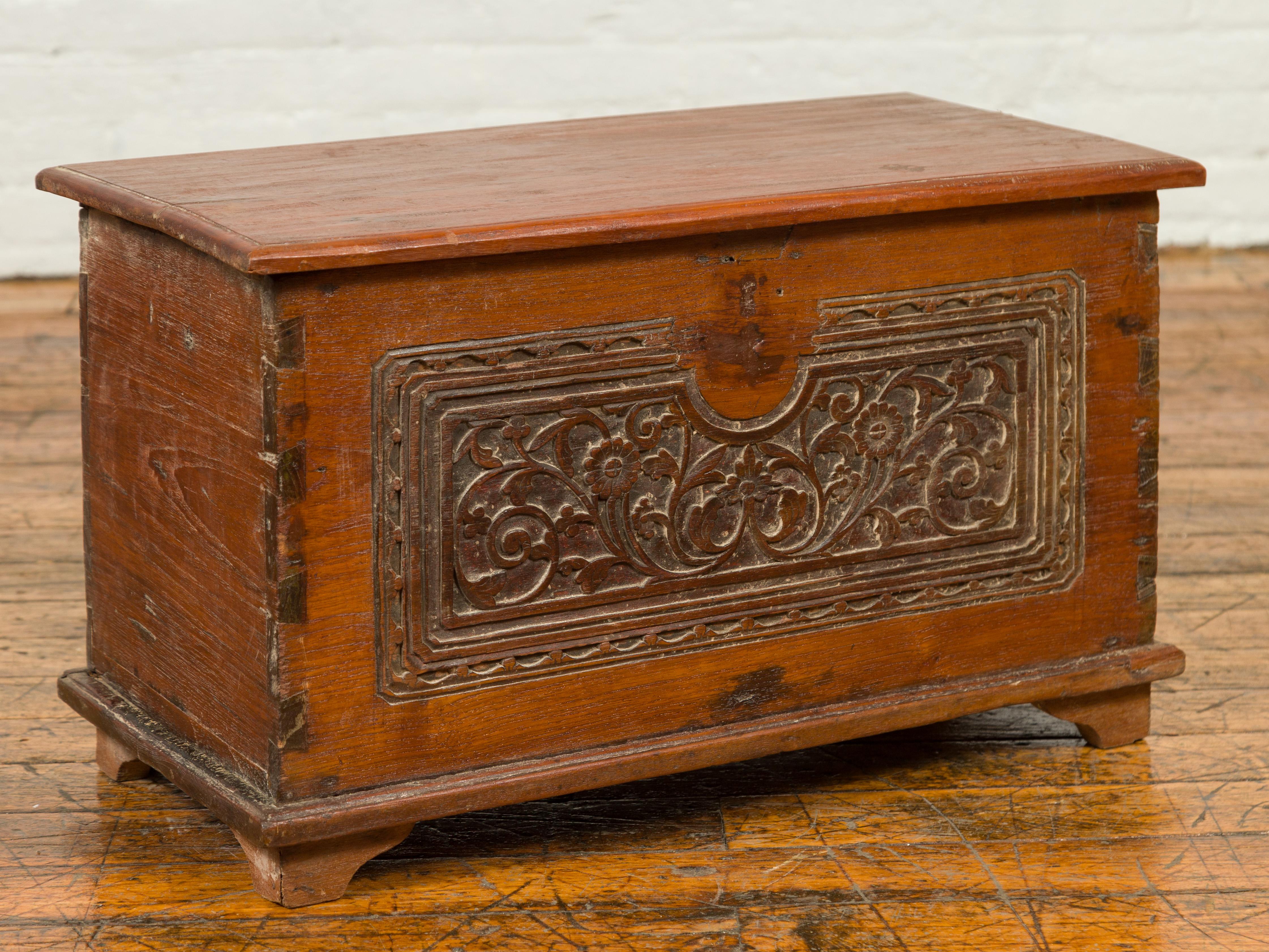 A vintage wooden blanket chest from the mid-20th century, with floral carved front, dovetailed construction and bracket feet. This mid-20th-century wooden blanket chest marries functionality with artistry, making it a versatile addition to any home