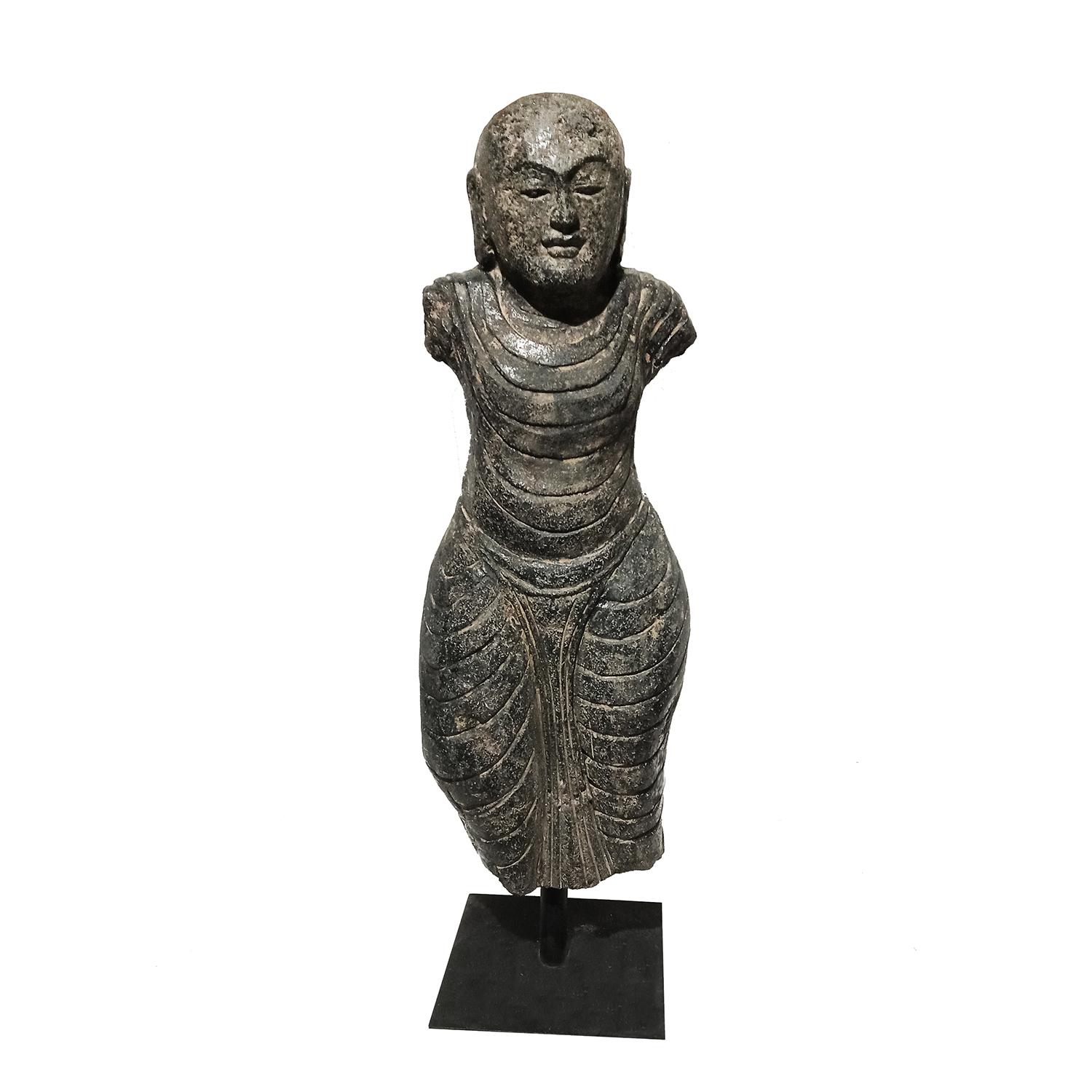 A volcanic black rock sculpture, hand-crafted in Indonesia, late 20th Century. Black Basalt, carved and polished. 

Depicting a torso in traditional attire, decorated throughout. Mounted on a black metal stand. Can be used indoors and outdoors.