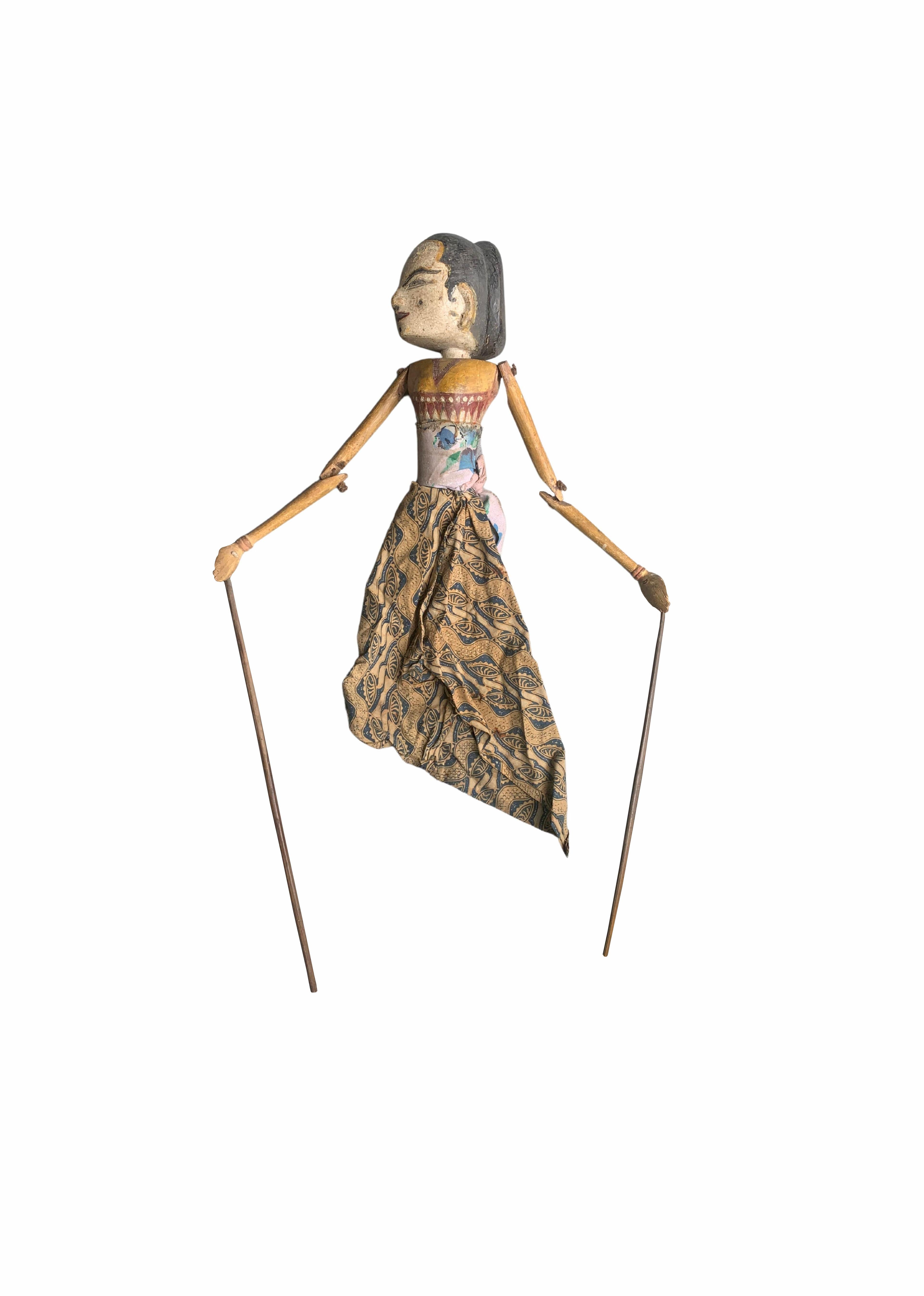 This “Wayang Golek” is a visibly old shadow puppet carved using soft wood and cloth. It features an articulated head and arms connected to rods, the dresses are made with batik fabric. Puppets such as these are used in shadow theatre to tell