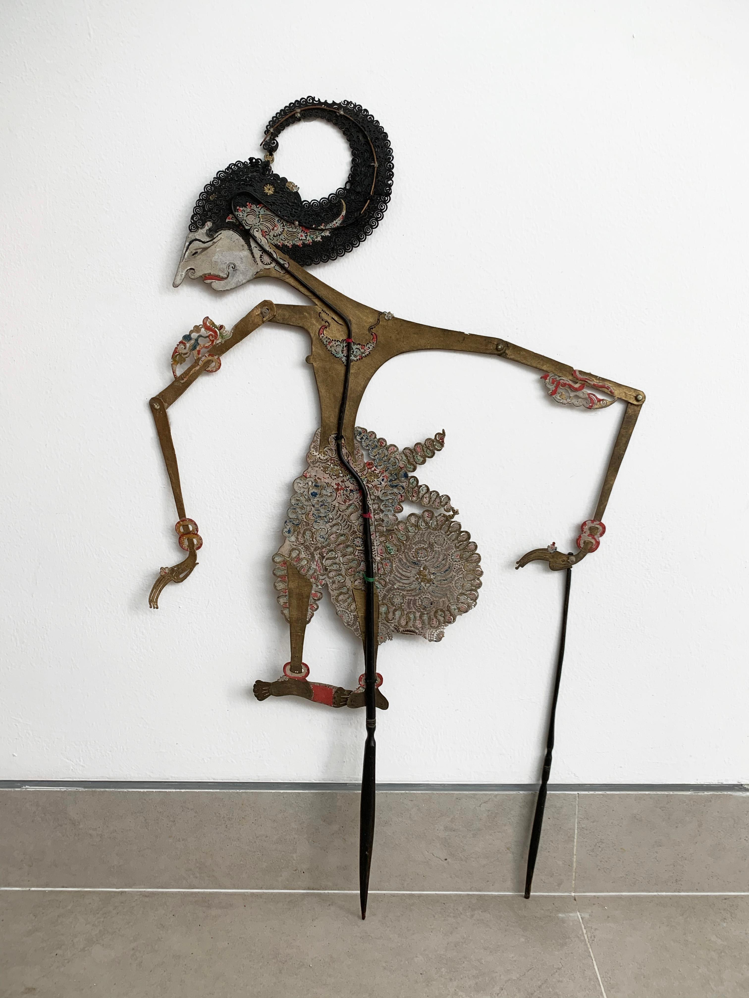 This flat shadow puppet was crafted on the island of Java by a puppet artist using buffalo hide and mounted on bamboo sticks. It features movable arms, controlled by outer bamboo rods (however this puppet lost one of its bamboo rods over the years