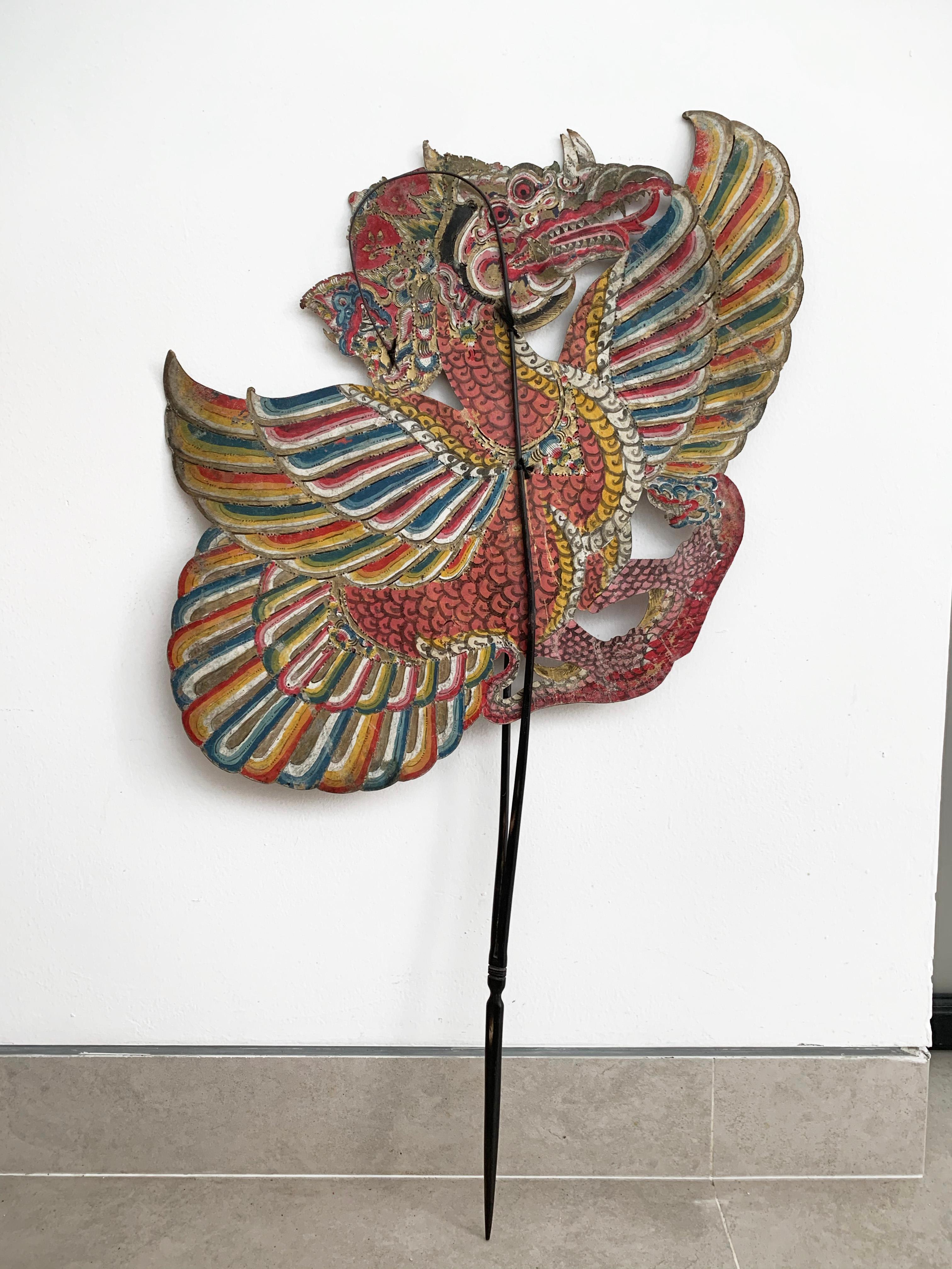Cette marionnette d'ombre plate représente un oiseau mythique. Elle a été fabriquée sur l'île de Java par un marionnettiste à partir de peau de buffle et montée sur des bâtons de bambou. Il était utilisé dans les spectacles de marionnettes Wayang,