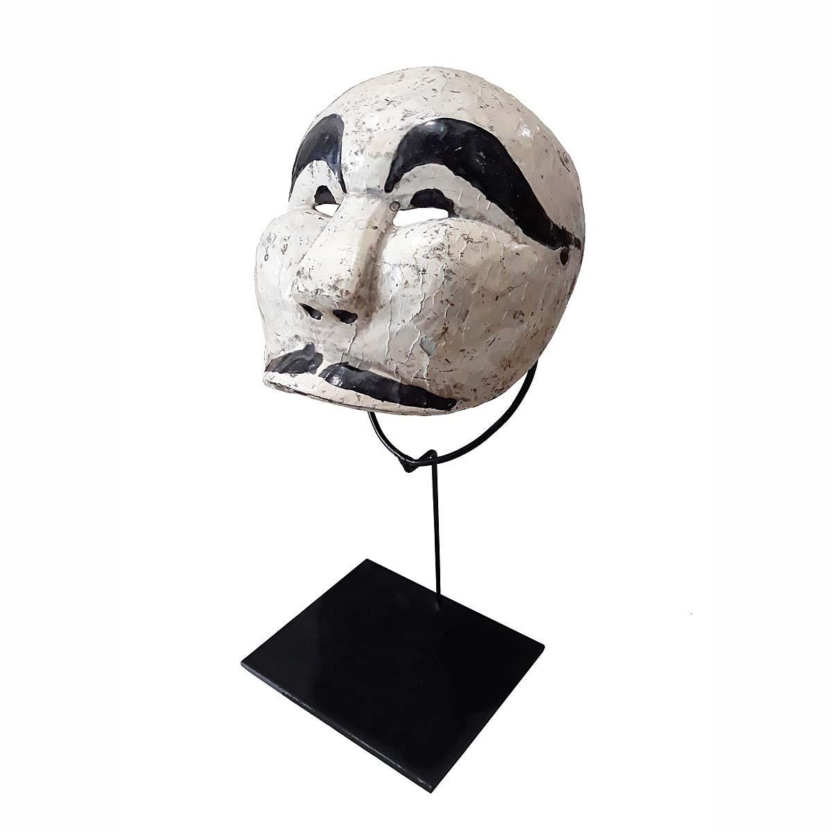 A vintage Penasar mask from Indonesia, circa 1975-1980. Hand-carved teak, polychromed in white and black. Mounted on a black metal stand. 

This type of mask is used at Indonesian Topeng or Mask theater dances, where traditional stories of nobles,