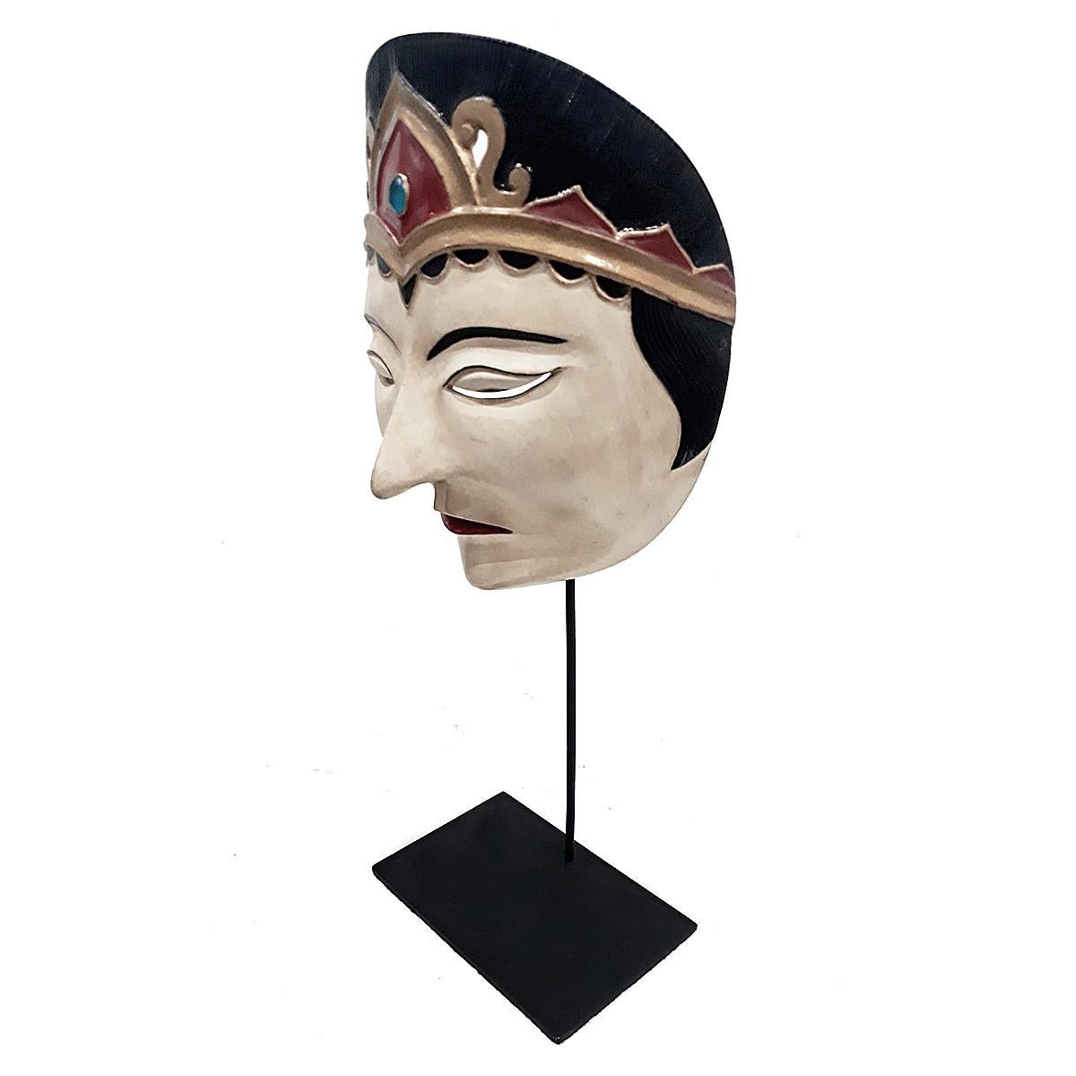 Eine alte Theatermaske aus Bali, Indonesien, ca. 1975-1980. 
Polychromiertes, handgeschnitztes Teakholz, montiert auf einem schwarzen Metallständer.

Diese Art von Maske wird bei indonesischen Topeng- oder Maskentheatertänzen verwendet, bei denen