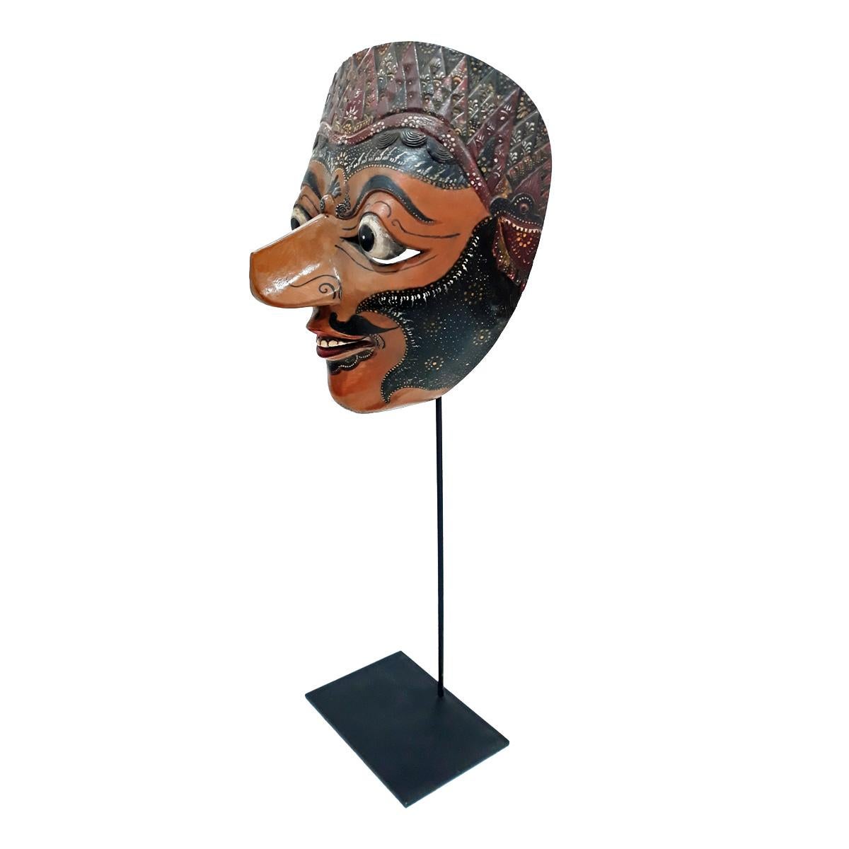 Masque de théâtre vintage de Bali, Indonésie, vers 1975-1980. 
Teck polychrome sculpté à la main, monté sur un socle en métal noir.

Ce type de masque est utilisé lors des danses indonésiennes Topeng ou théâtre des masques, où des histoires