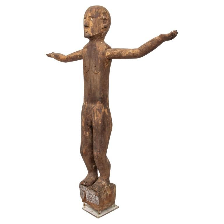 Indonesian Wood Patung Polisi Guardian Sculpture, 19th century, West Borneo, depicting standing male figure with arms outstretched, with white shells for eyes, standing on wood base with carved letters, some chipping and losses to wood base, and