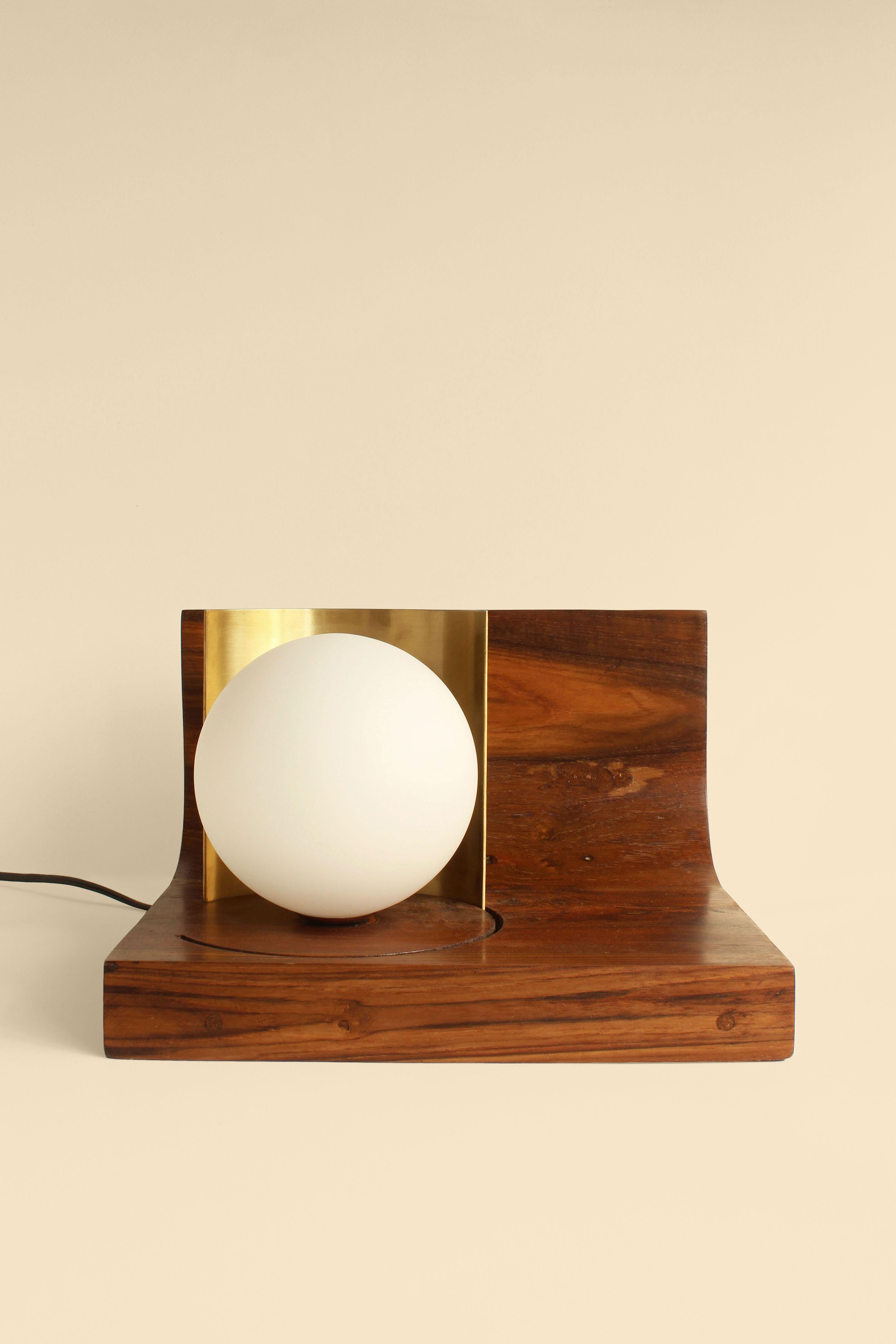 Indu Table Lamp by Studio Indigene
Dimensions: D 26.67 x W 24.13 x H 16.51 cm
Materials: Reclaimed Teak Wood, Brass, Glass Globe. 
Colors Brown, Natural Wooden Finish.

Indu, waxing and waning; goes from a table lamp to a night lamp, the moving
