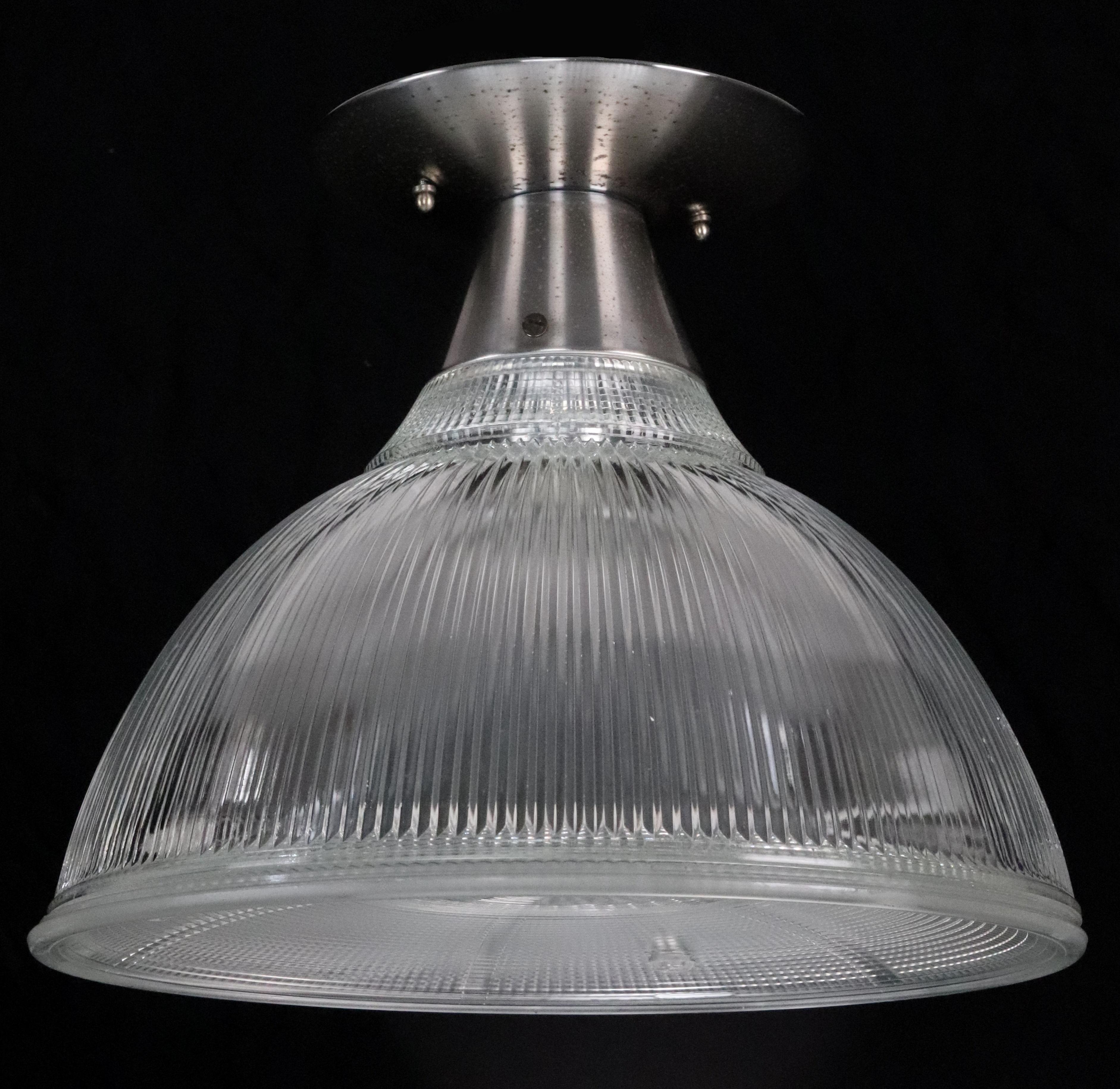 Cette lampe encastrée de style industriel est dotée d'un abat-jour en Holophane prismatique transparent, d'une lentille inférieure et d'un adaptateur en acier brossé pour montage encastré. Chaque lampe nécessite une ampoule à culot moyen standard