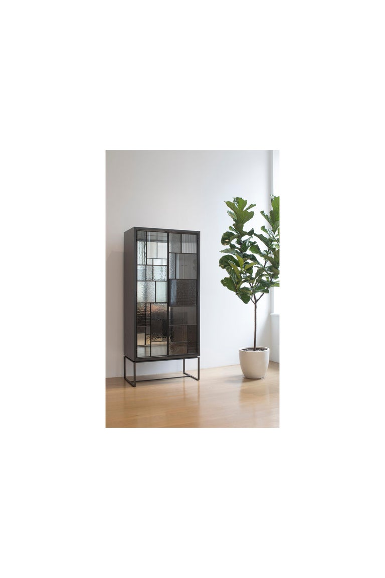 The industrial 2 door vitrine by Ercole home is a one of a kind statement piece that is bound to liven up your space. This vintrine is made up of a unique combination of hand cut glass all varying in size, color, and texture making each door like