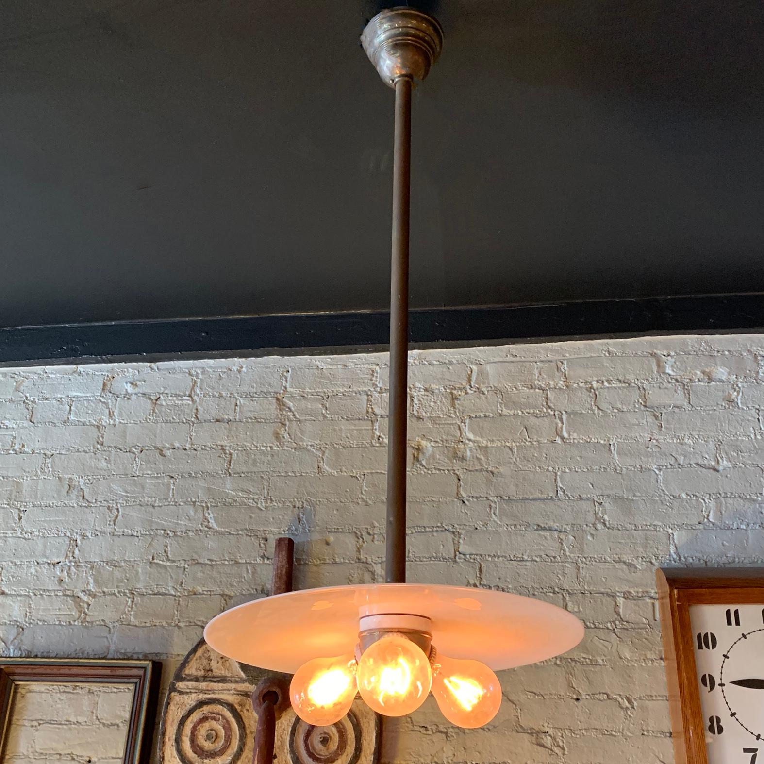 Industrial pendant light features a flat 16 inch, milk glass disc with a brass and porcelain, 3 bulb, Benjamin socket on a brass pole with matching ceiling canopy. The pendant is newly wired to accept up to three 100 watt bulbs.