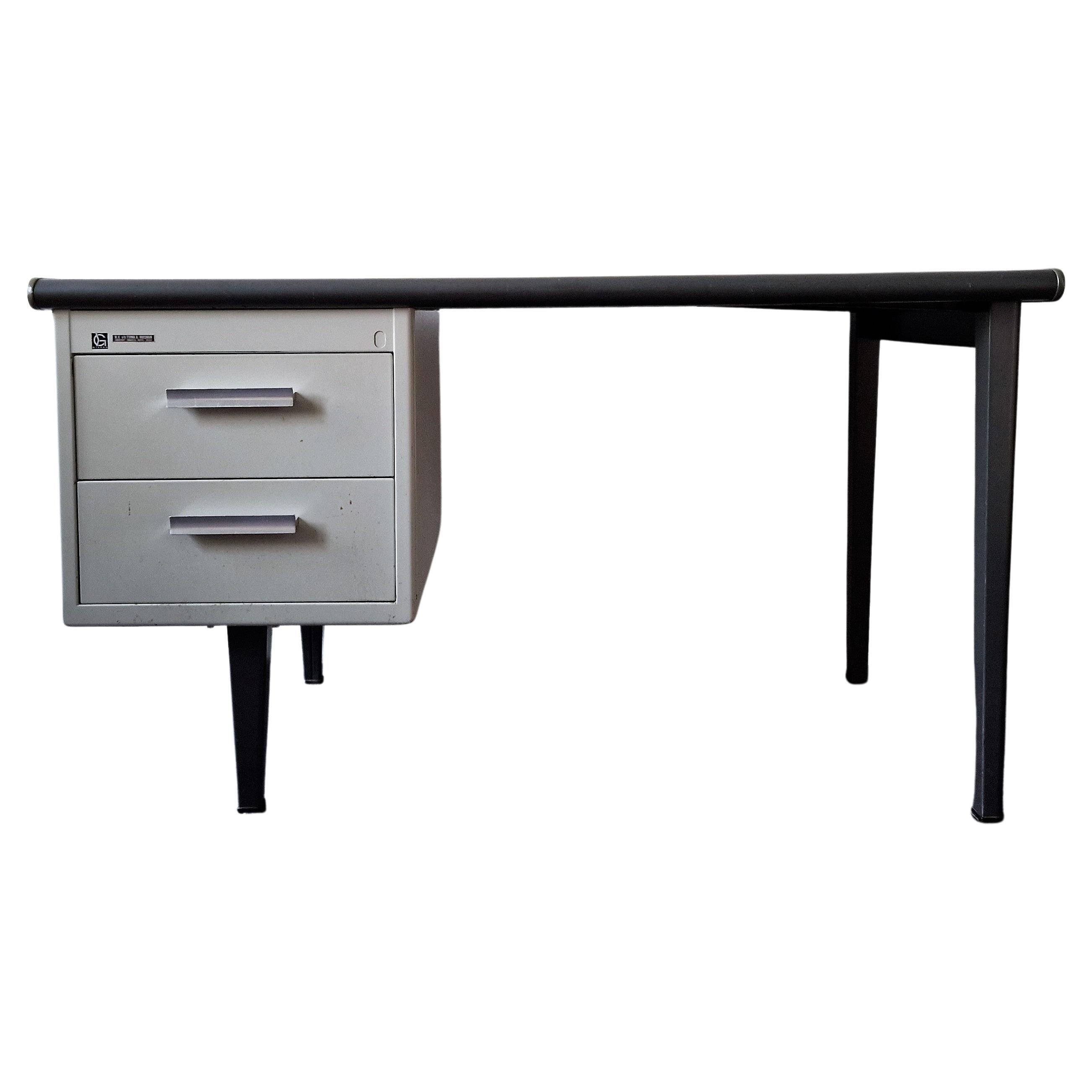 This industrial desk was designed as a writing machine desk by André Cordemeyer for N.V. Gispen. It is part of the 7900 series. The desk has a metal base with high tapered leggs, 2 drawers with aluminum handles and a dark grey linoleum top. It is