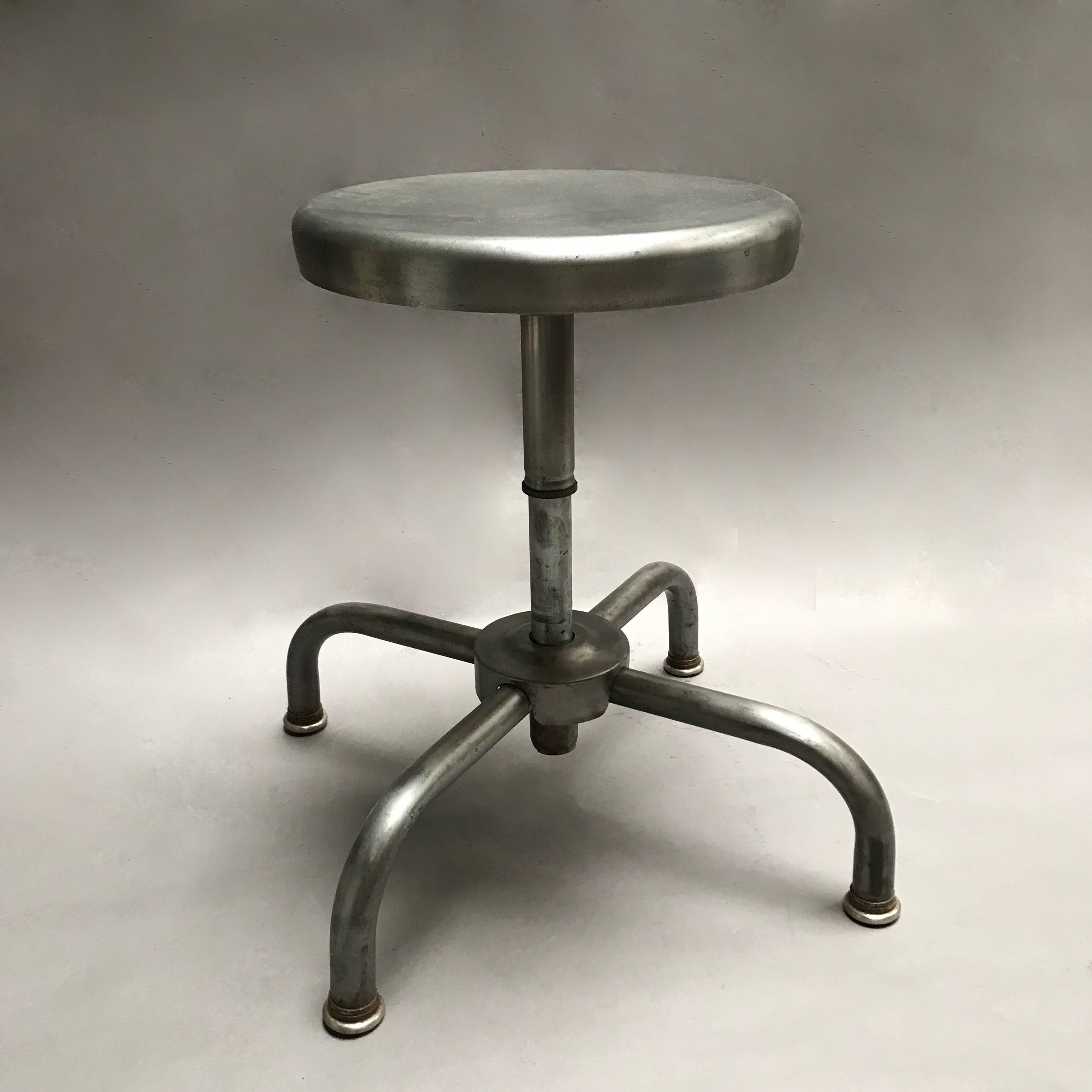 Industrial, adjustable, laboratory stool with newly brushed finish, features a four prong base and 13 inch diameter swivel seat. The seat height is easily adjustable from 15 - 20 inches.