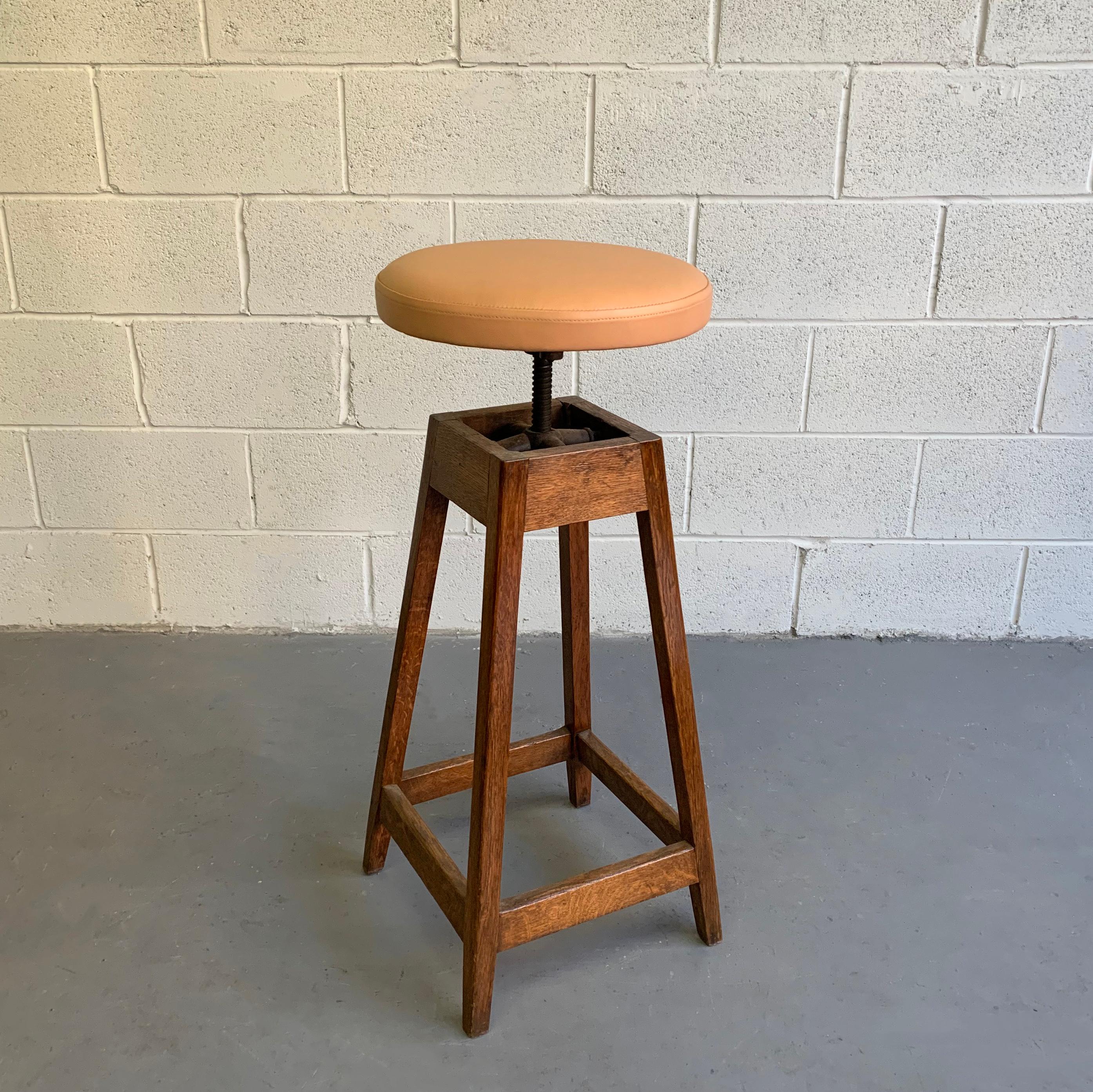 Industrial, oak, shop stool with newly upholstered, 14 inch round, leather seat is height adjustable from 29-33 inches.