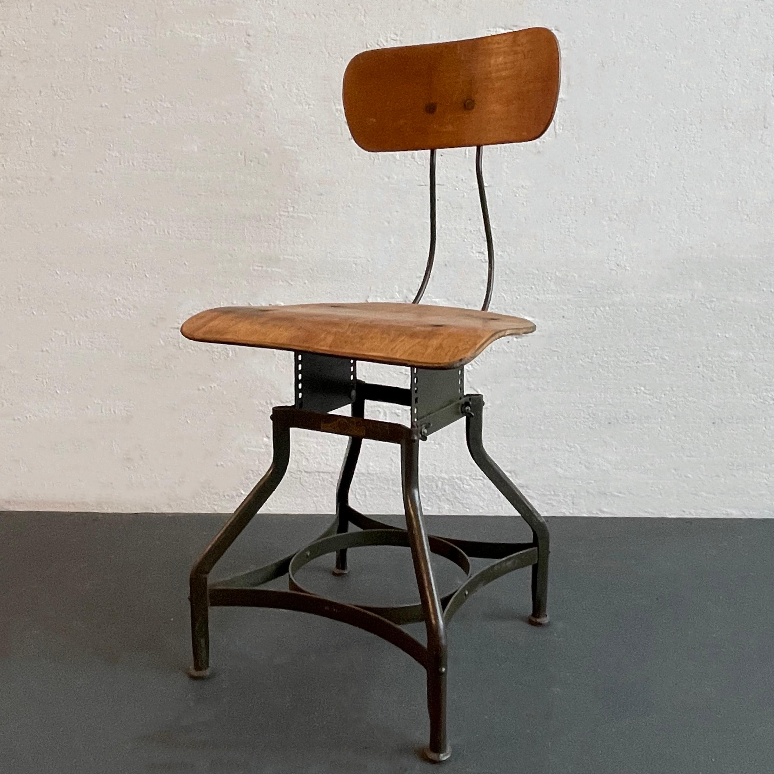 Esta silla industrial ajustable de Toledo Metal Furniture Co. tiene la característica base de acero pintado en estrella de Toledo con asiento y respaldo de arce curvado. La altura de la silla se puede ajustar de 15 a 18 pulgadas colocando la placa