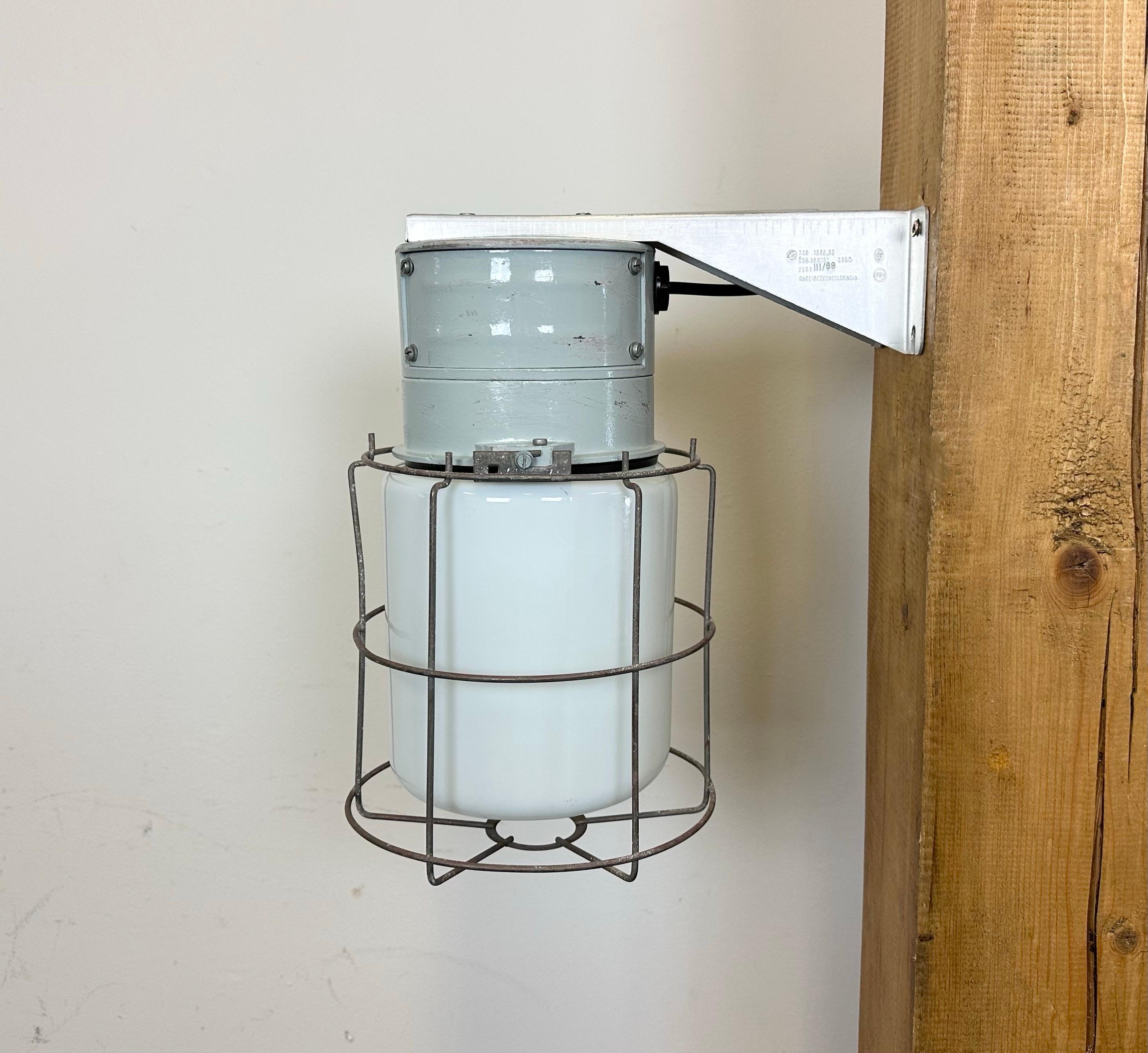 This Industrial wall light was made by Elektrosvit in former Czechoslovakia during the 1970s. It features a cast aluminium wall mounting,an iron grid and a milk glass cover. New porcelain socket requires standard E 27/ E26 light bulbs. New wire. The