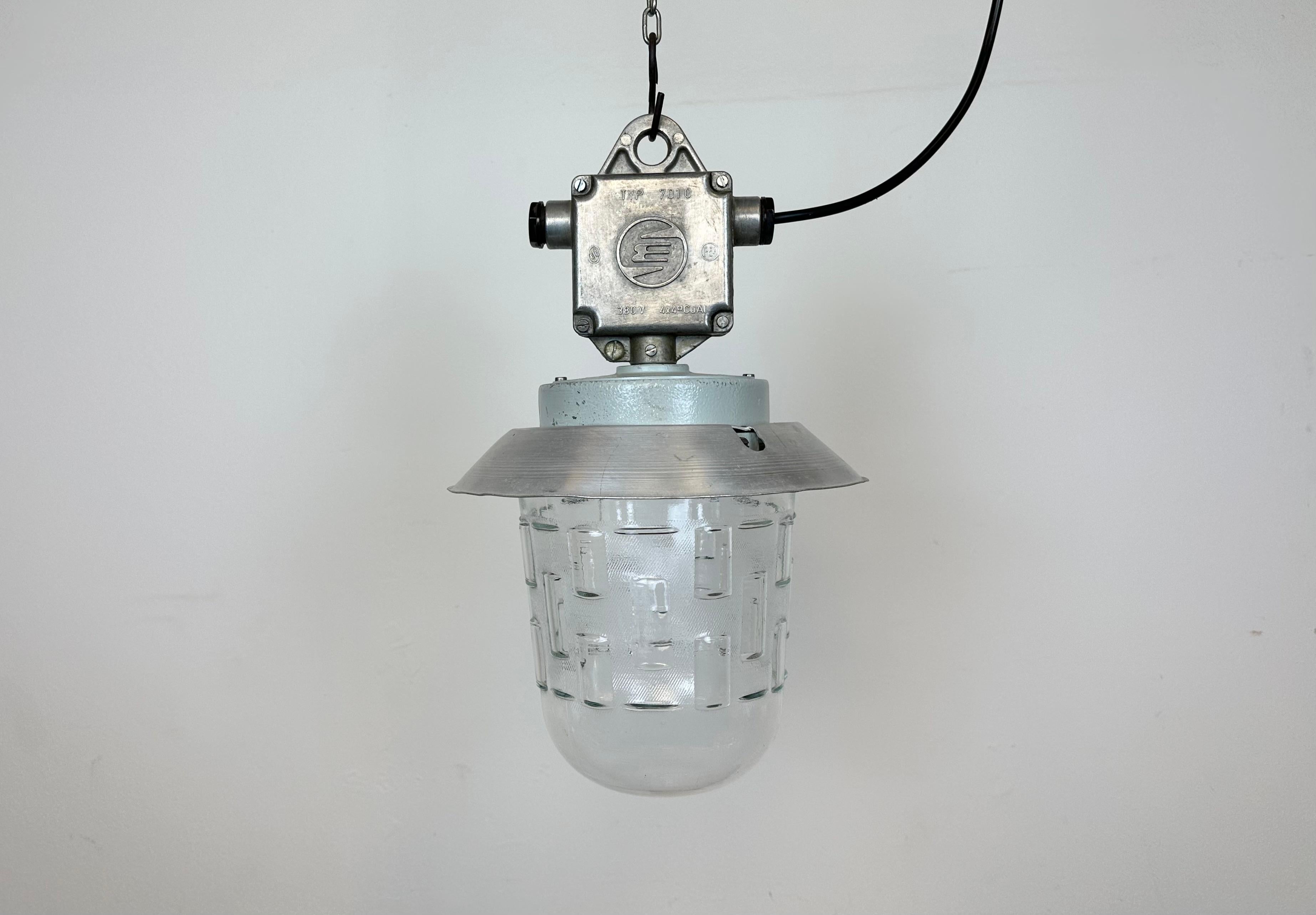 This Industrial hanging light was made by Elektrosvit in former Czechoslovakia during the 1970s. It features a cast aluminium top, an aluminium shade and a  glass cover. New porcelain socket requires standard E 27/ E26 light bulbs. New wire. The