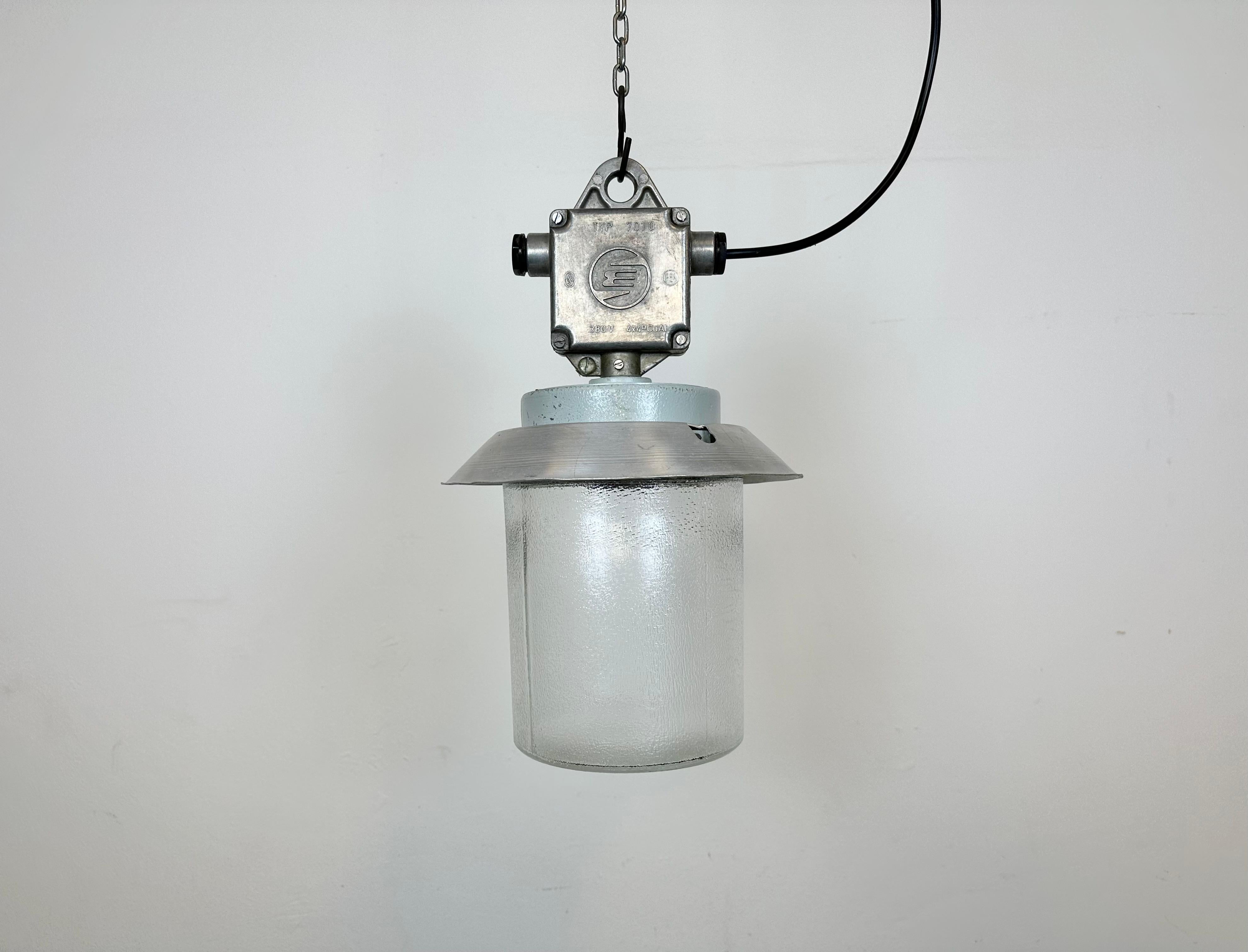 This Industrial hanging light was made by Elektrosvit in former Czechoslovakia during the 1970s. It features a cast aluminium top, an aluminium shade and a frosted glass cover. New porcelain socket requires standard E 27/ E26 light bulbs. New wire.