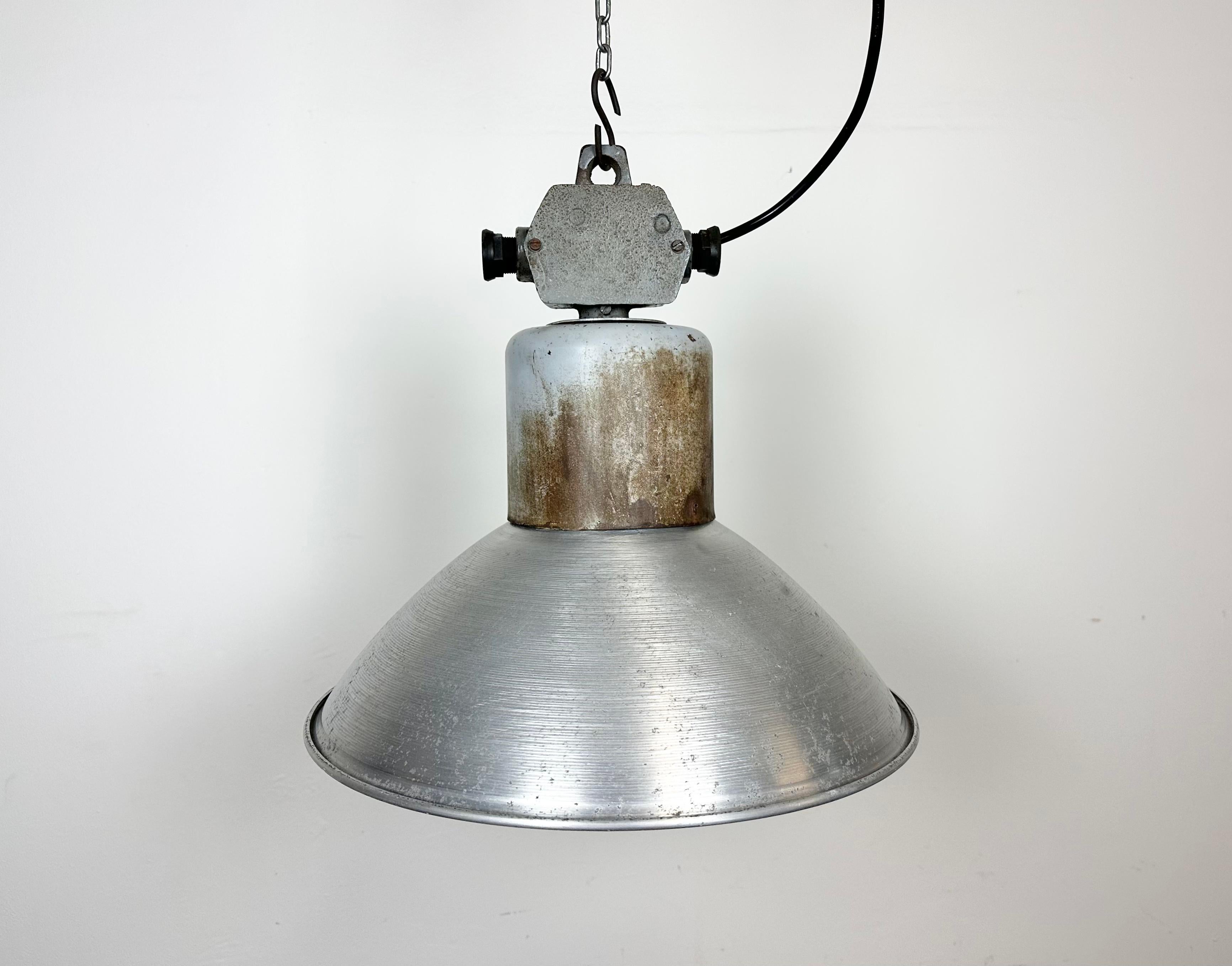 This industrial factory pendant lamp was made by Polam Wilkasy in Poland during the 1960s. It features an aluminium shade and iron top with cast aluminium box. New porcelain socket requires E27/ E26 light bulbs. New wire. The piece weighs 2.1 kg.The