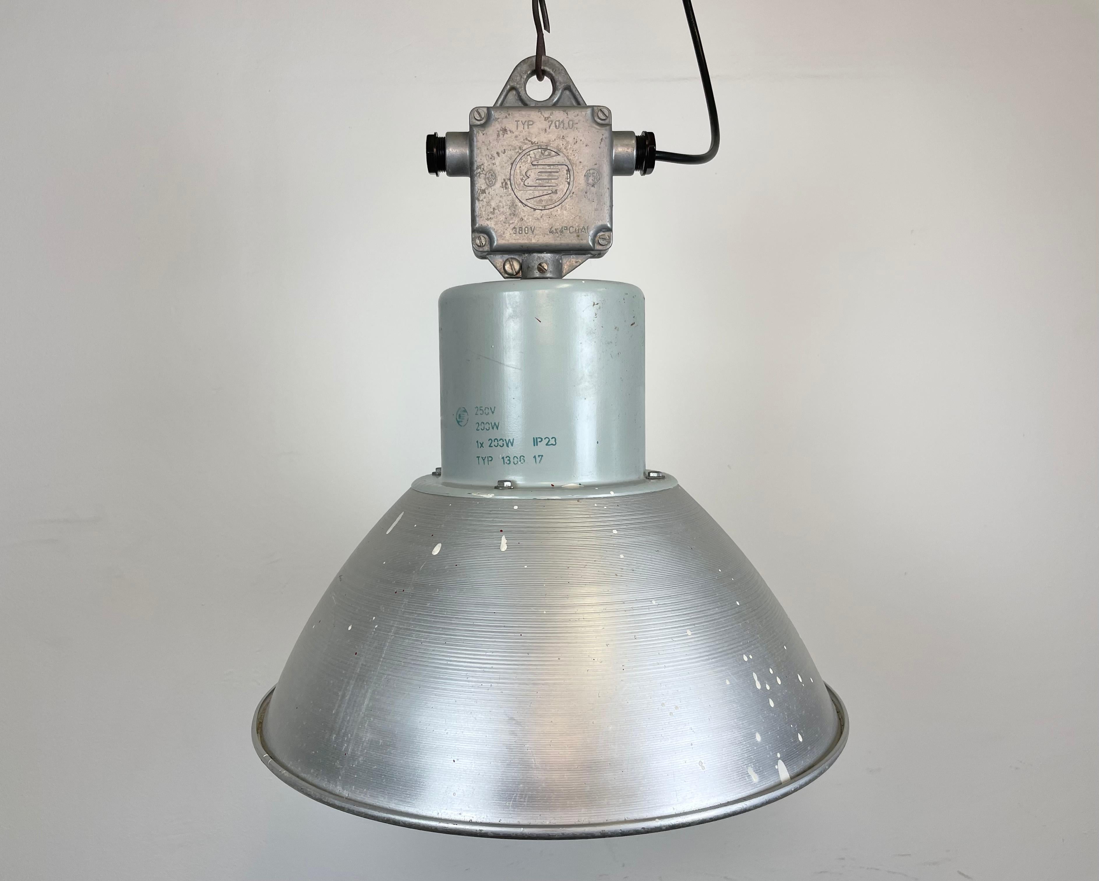 This pendant lamp was made by Elektrosvit and originally used in a factories in former Czechoslovakia in the 1960s. The piece is comprised of an aluminium lampshade and a cast aluminium top. The lamp is fully functional and features a new porcelain