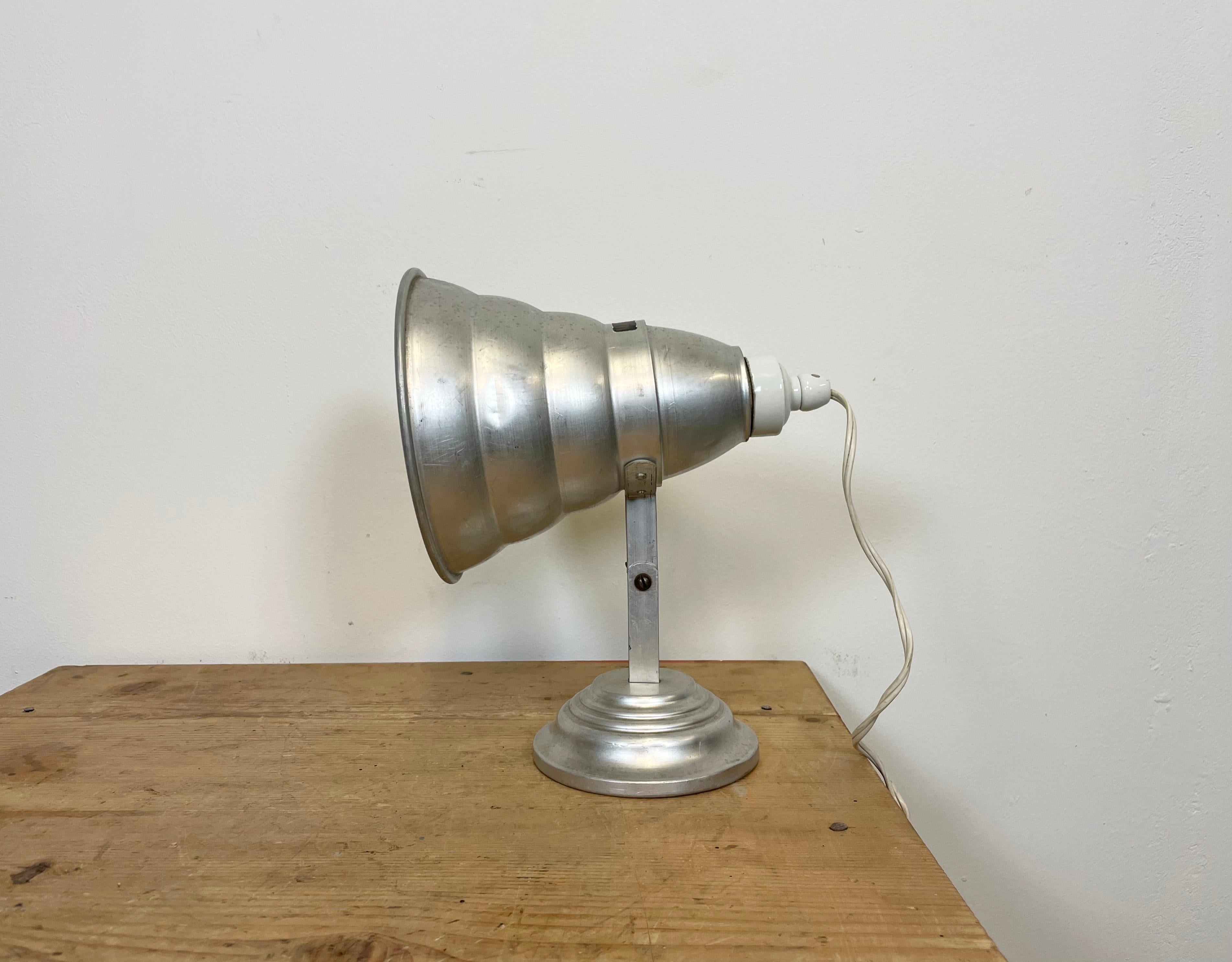 Vintage industrial table lamp from the 1960s. It features an aluminium shade, base, arm with one adjustable joint and a porcelain top with switch. The socket requires E 27 light bulbs. The diameter of the shade is 18 cm. Good vintage condition.