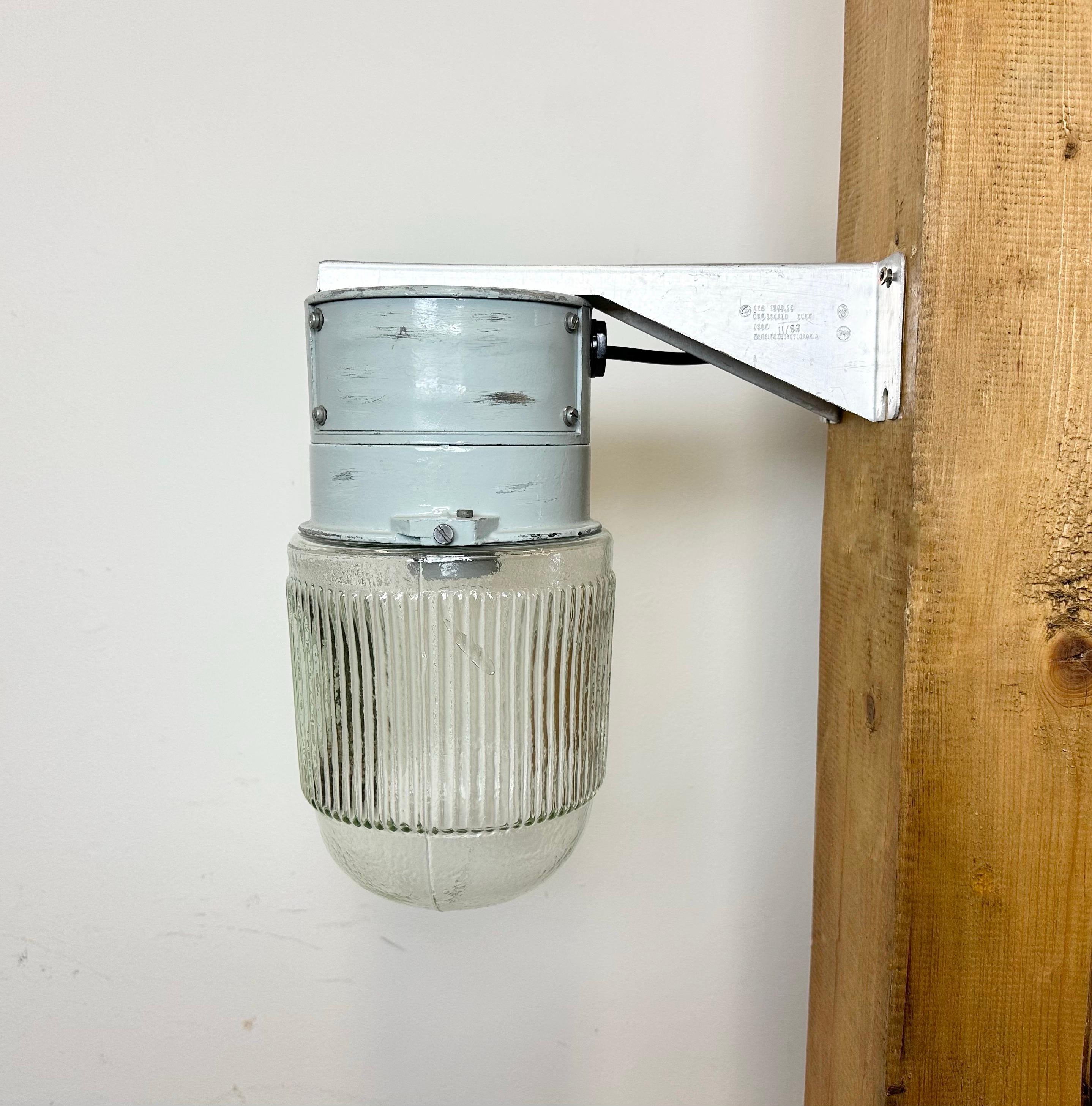 This Industrial wall light was made by Elektrosvit in former Czechoslovakia during the 1970s. It features a cast aluminium wall mounting and a ribbed glass cover. New porcelain socket requires standard E 27/ E26 light bulbs. New wire. The weight of