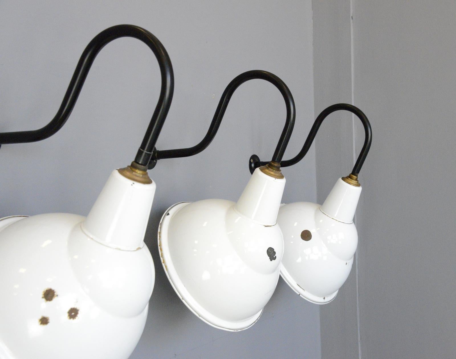 Industrial angled wall lights by Benjamin, circa 1950s

- Vitreous white enamel 
- Curved steel wall brackets
- Takes E27 fitting bulbs
- Wires directly into the wall
- Made by Benjamin
- English, 1950s
- Measures: 33cm wide x 43cm tall x