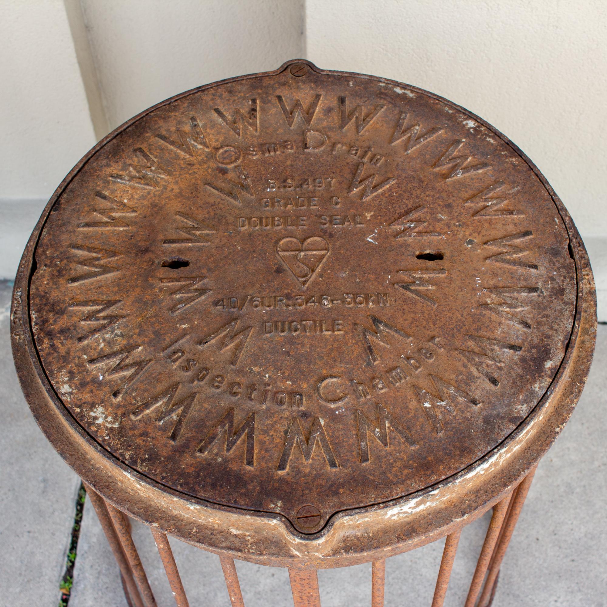 This patinated iron piece is actually a manhole cover and drain that makes a fantastic side table. The top of the manhole is cast with wonderful details and attached is a grate or drain structure, which serves as the table base. This piece is