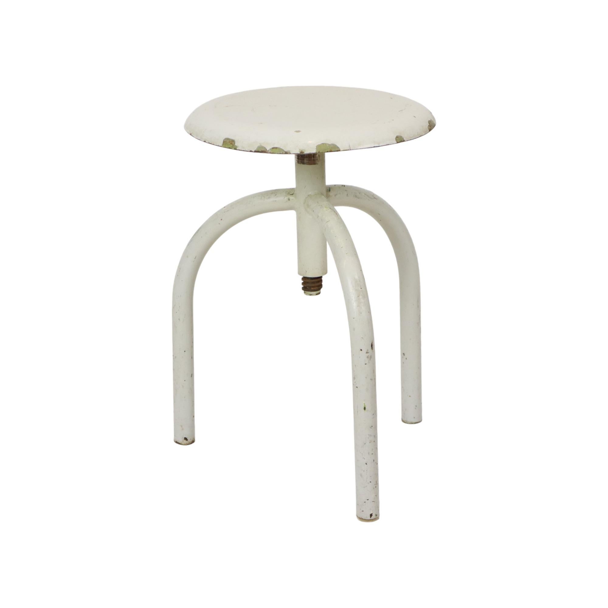 Cool industrial antique doctor's stool, lab stool, made of white painted metal, authentic medical object from mid 20th century.

The stool is adjustable in height and is marked by the distributor, J. Van Den Daelen, Geraardsbergen, Belgium.

In very
