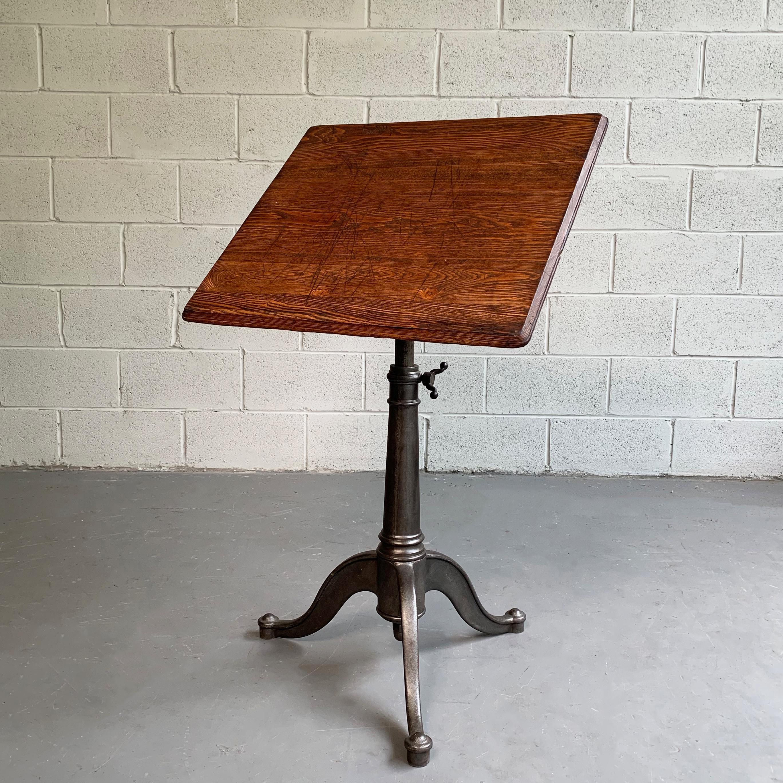 Small, antique, artist rendering easel table features an oak top on a tilt and height adjustable, cast iron, pedestal base that adjusts from 29 - 40 inches height.