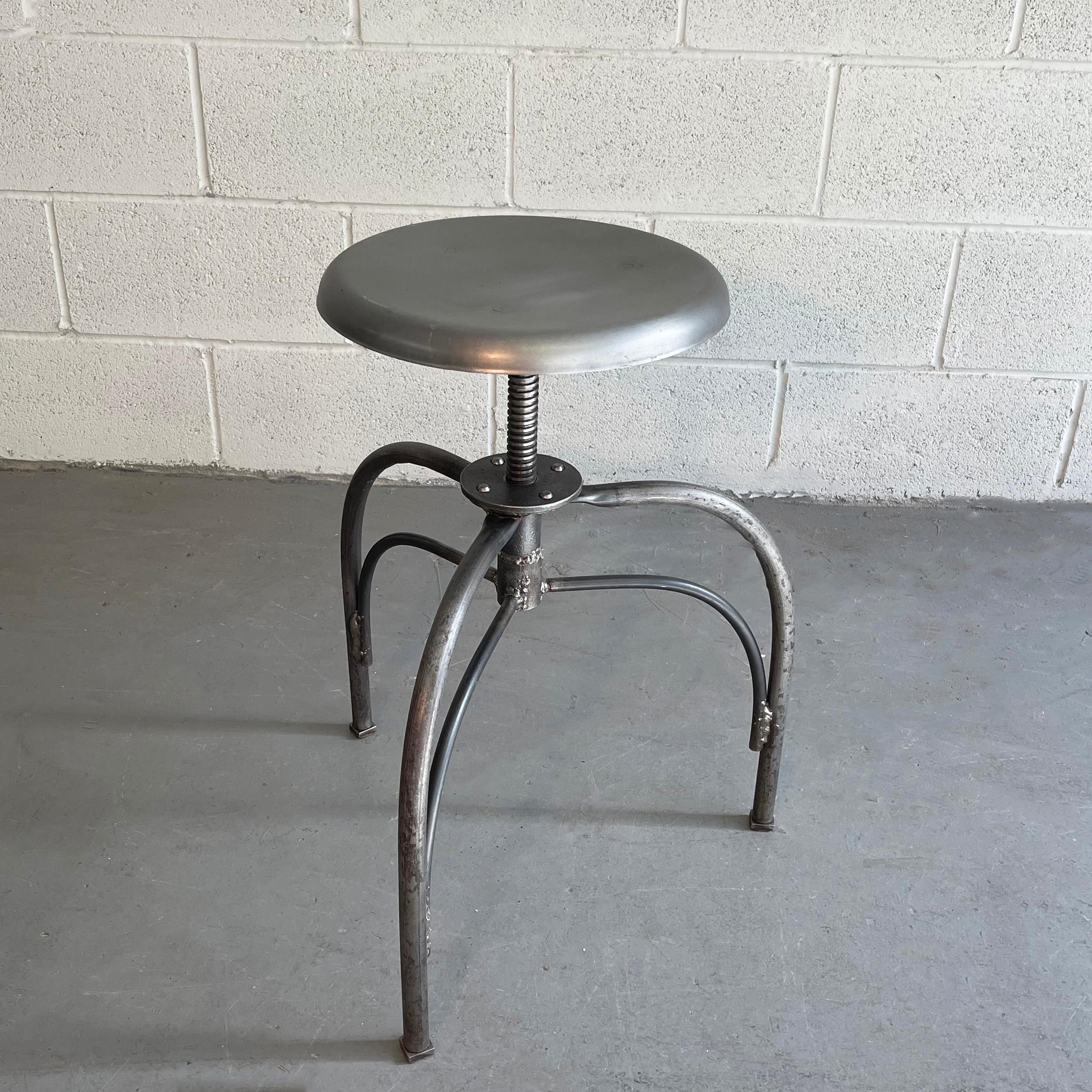 Early 20th century, industrial, brushed steel, hospital, examination stool features a 14 inch diameter, swivel seat that is height adjustable from 18 - 24 inches.